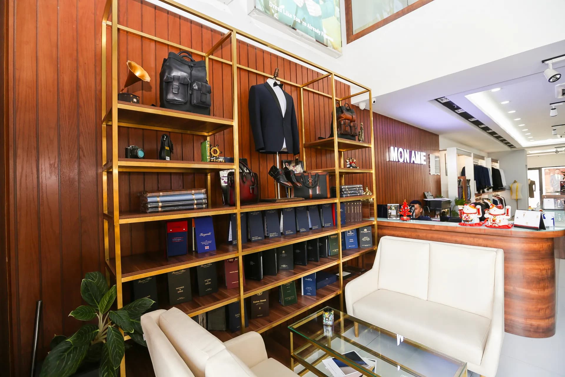Góc showroom ốp gỗ với kệ vàng đồng trưng bày vest, cặp da, giày