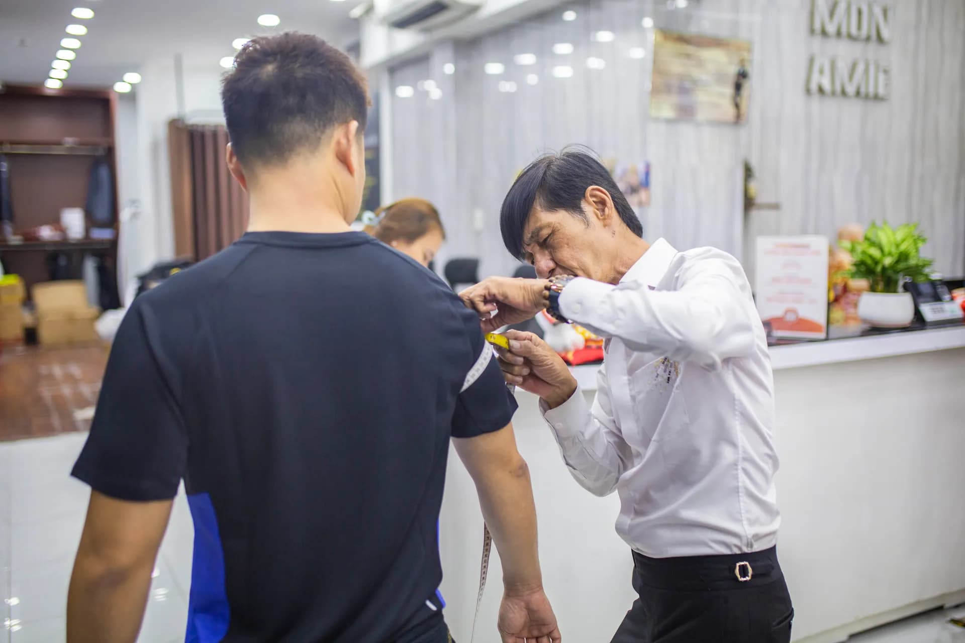 Thợ may đo vai cho khách áo thun đen, cận cảnh khoảnh khắc đo may