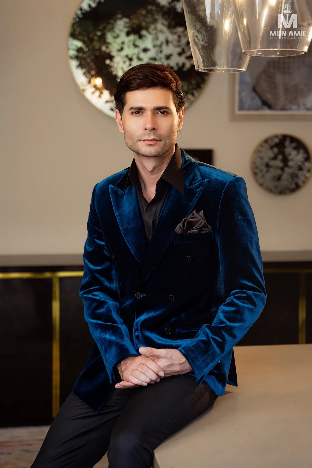 Blazer nhung xanh ngồi tại quầy bar, chất nhung bắt sáng nổi bật.