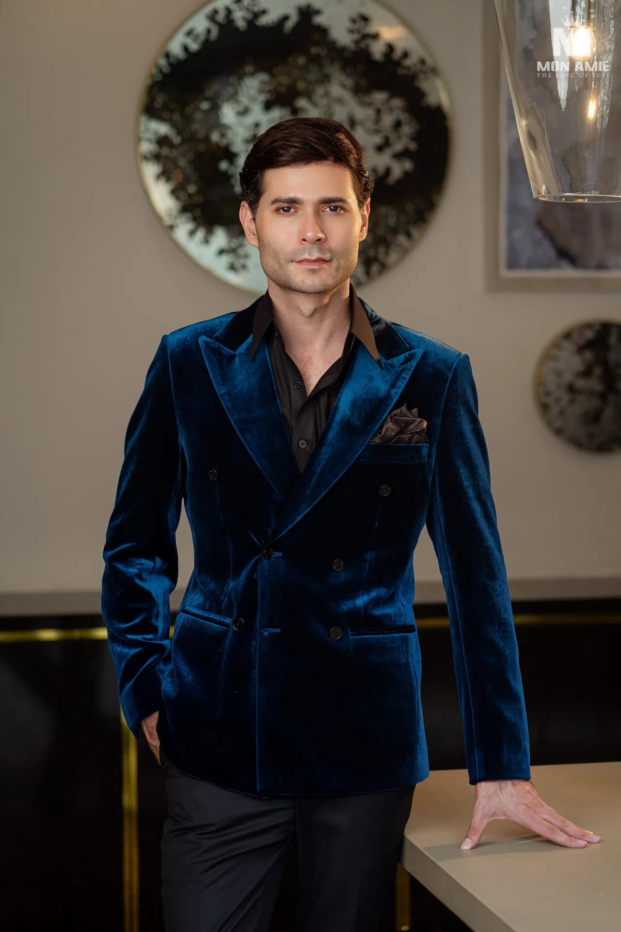 Blazer nhung xanh cobalt, khăn cài túi, dựa mép bàn đá
