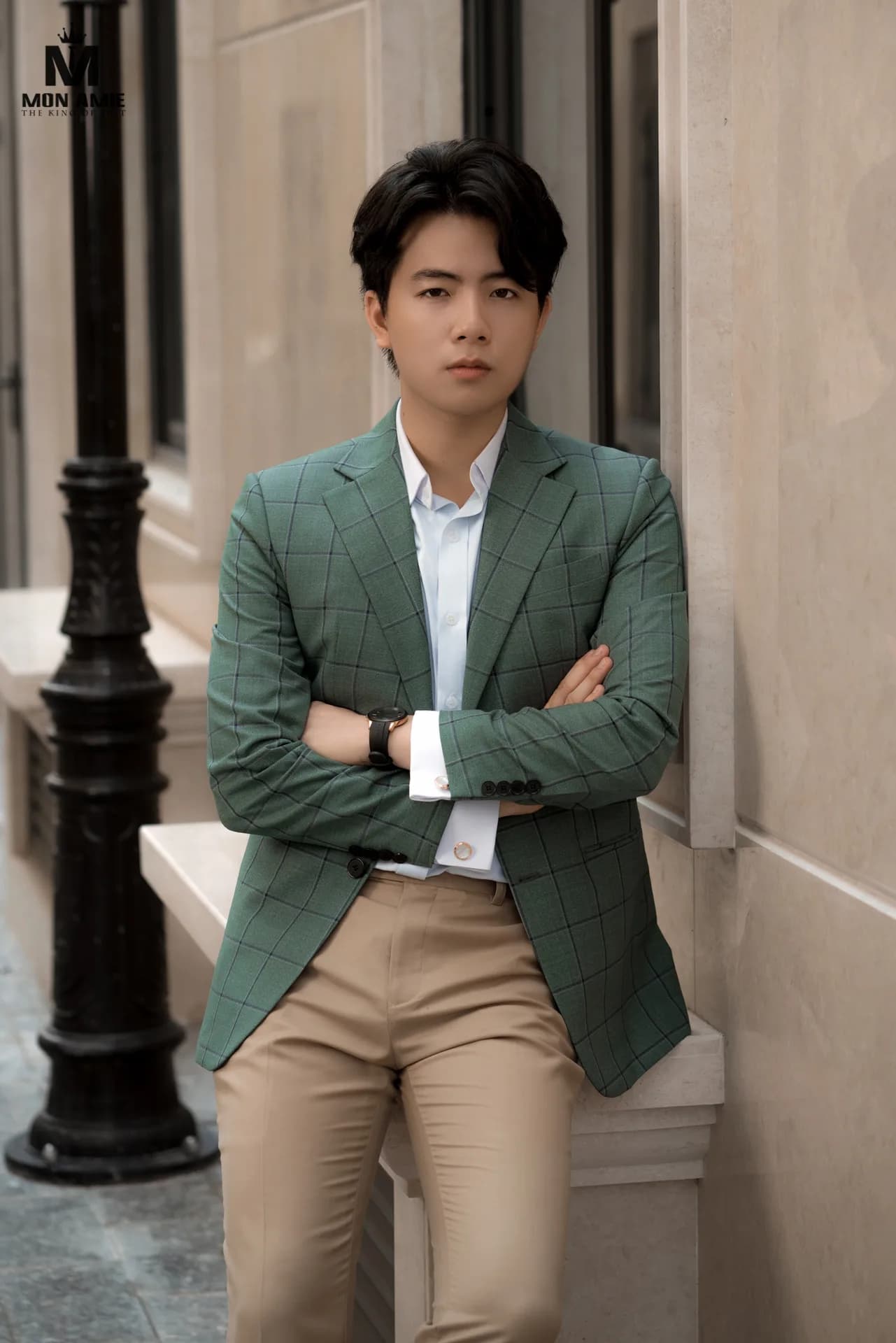 Blazer caro xanh lá phối sơ mi xanh nhạt, quần be, khoanh tay