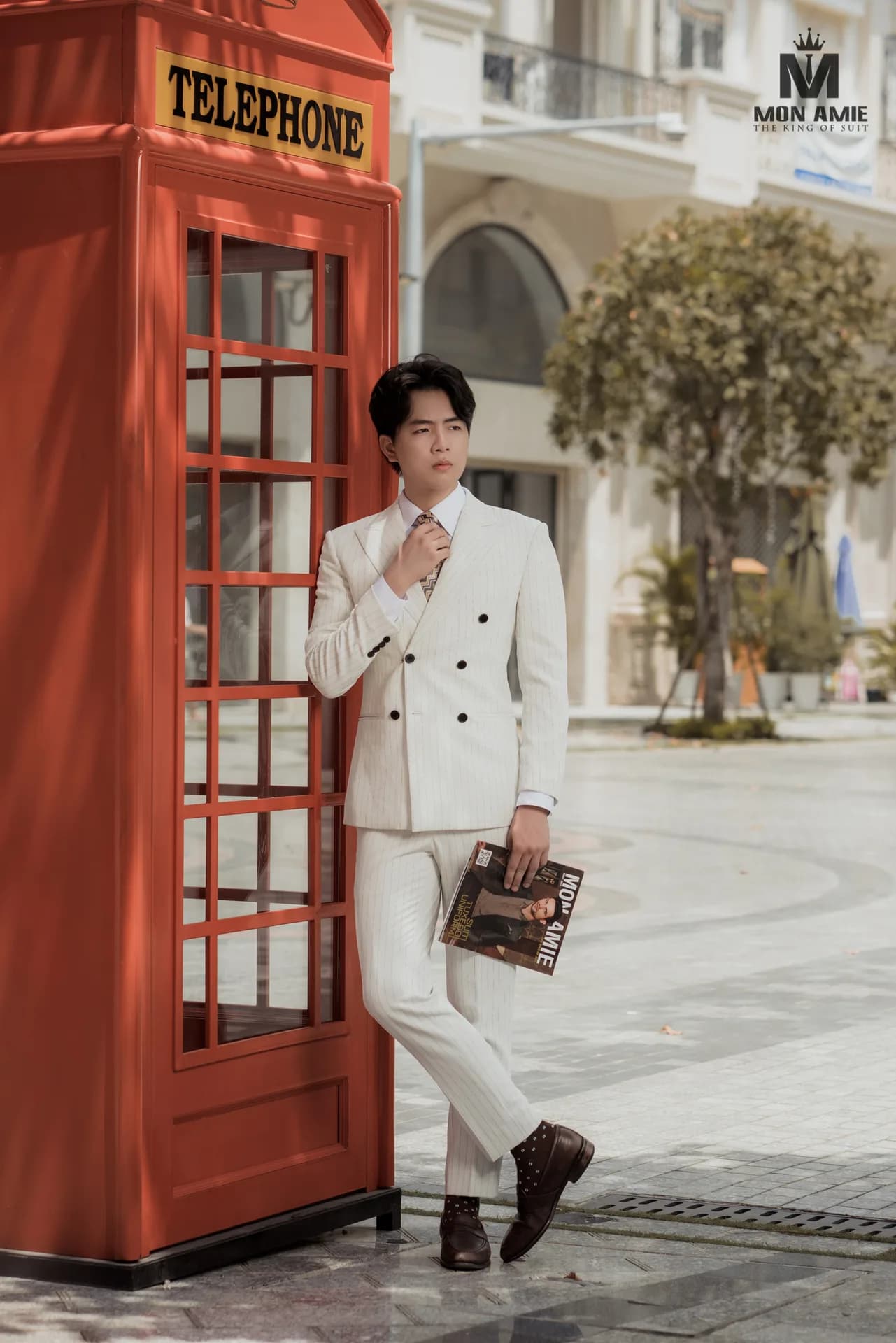 Suit kem sọc hai hàng khuy, dựa bên buồng điện thoại đỏ