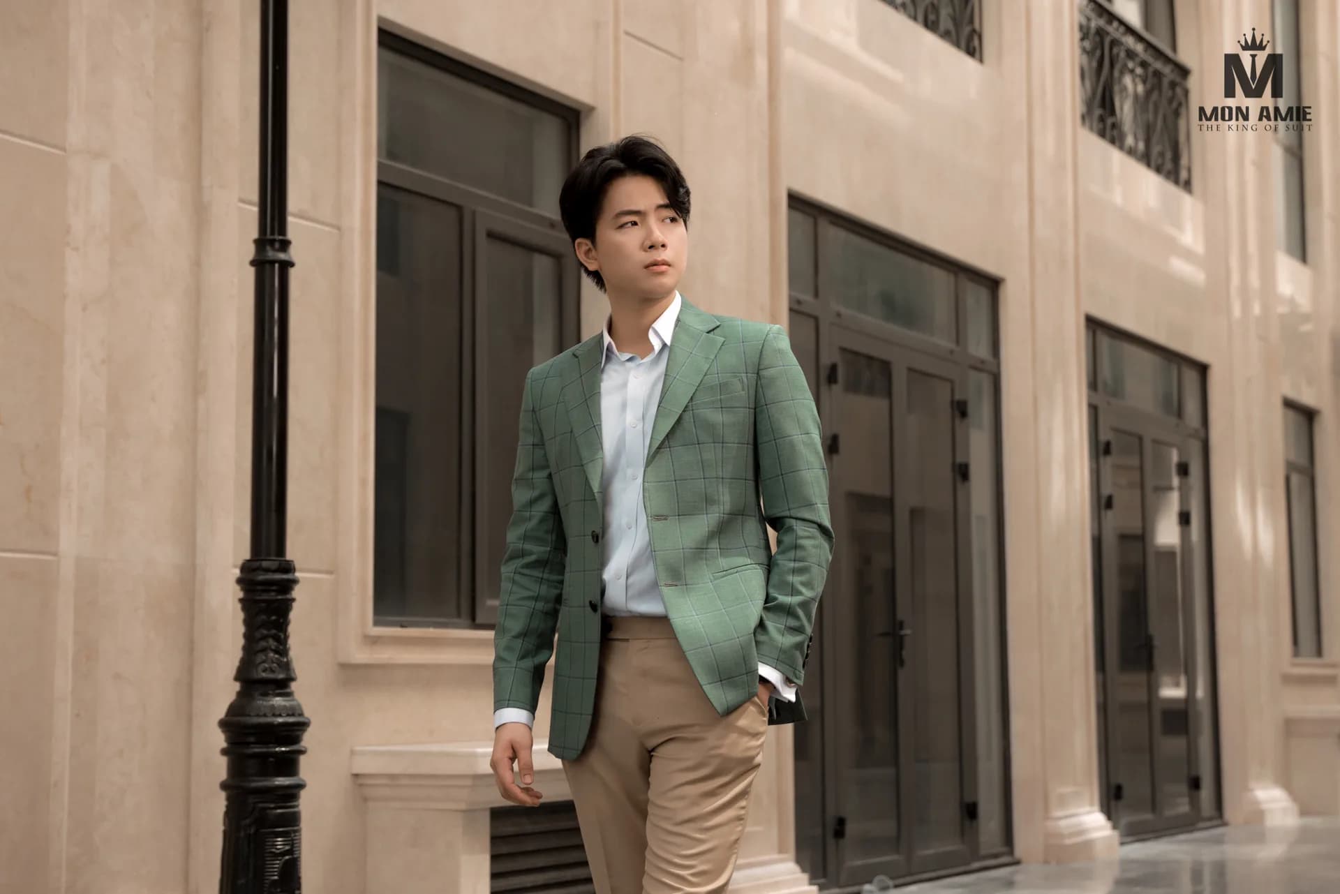 Blazer caro xanh lá, tay đút túi, dạo bước bên phố đá sáng