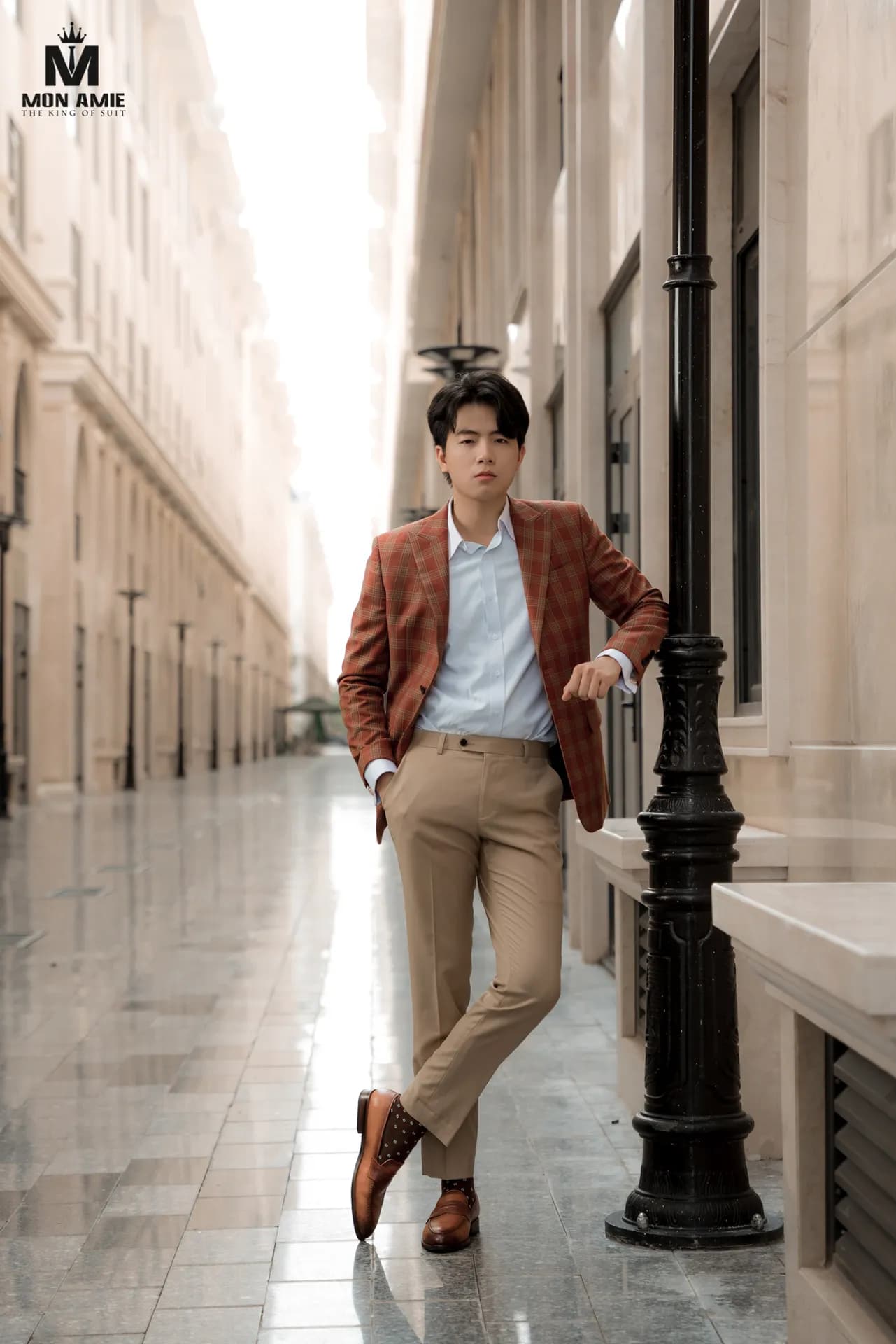 Blazer caro cam gạch, quần kaki, đứng chéo chân bên cột đèn dãy phố