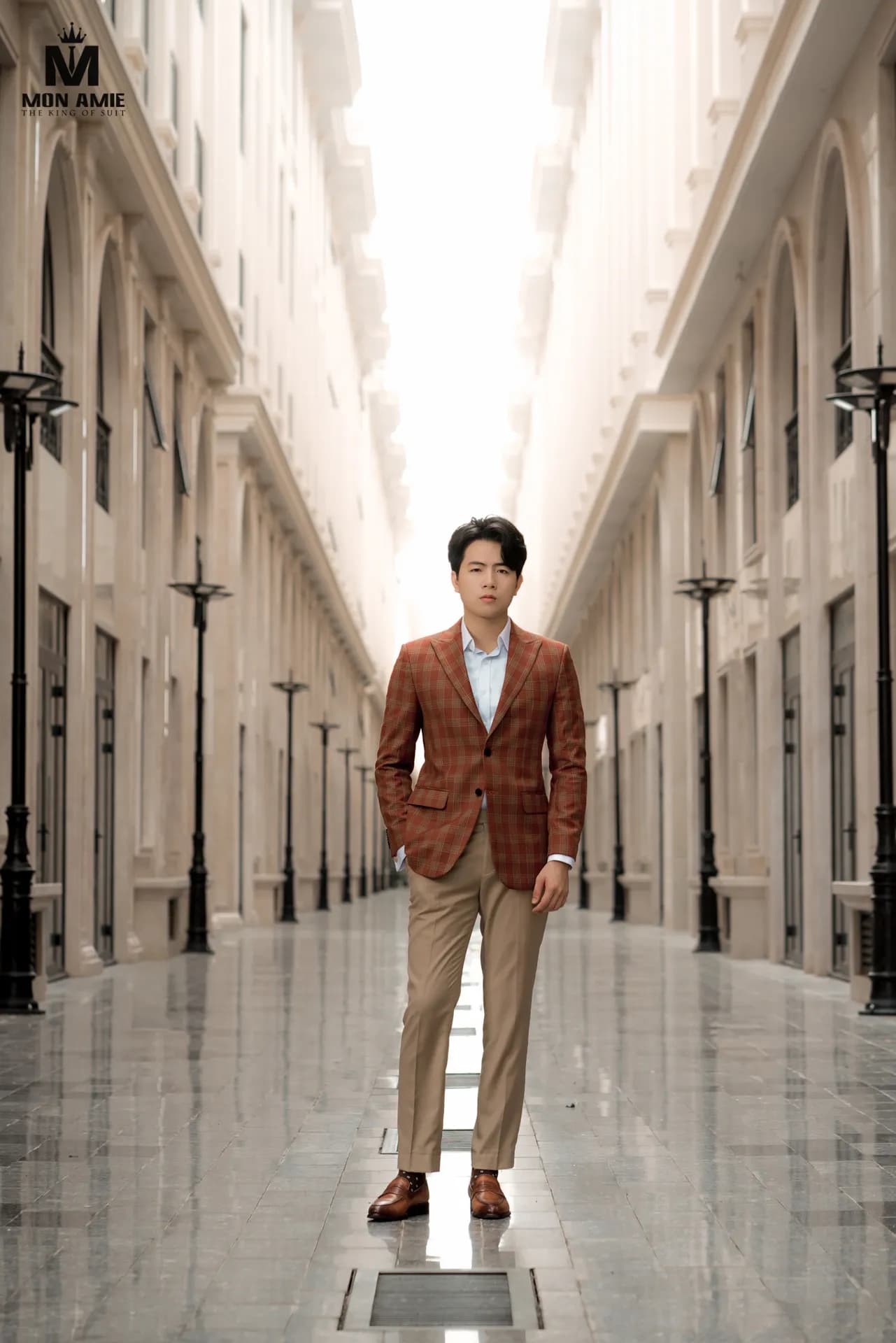 Blazer caro cam gạch, quần kaki, đứng giữa con phố vòm cổ điển