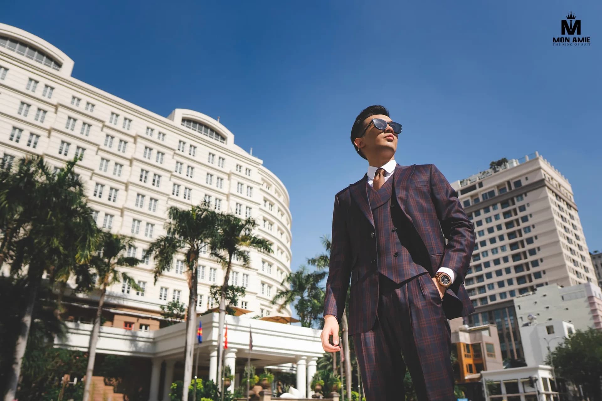 Suit ba mảnh caro nâu đỏ chụp góc thấp trước tòa nhà cổ giữa nắng Sài Gòn