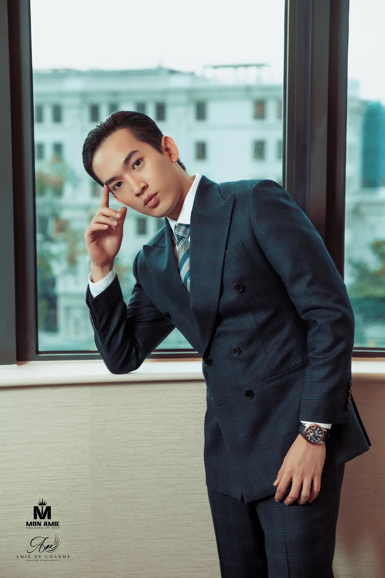 Suit hai hàng khuy xanh navy kẻ ô, cà vạt sọc, dáng tựa cửa sổ