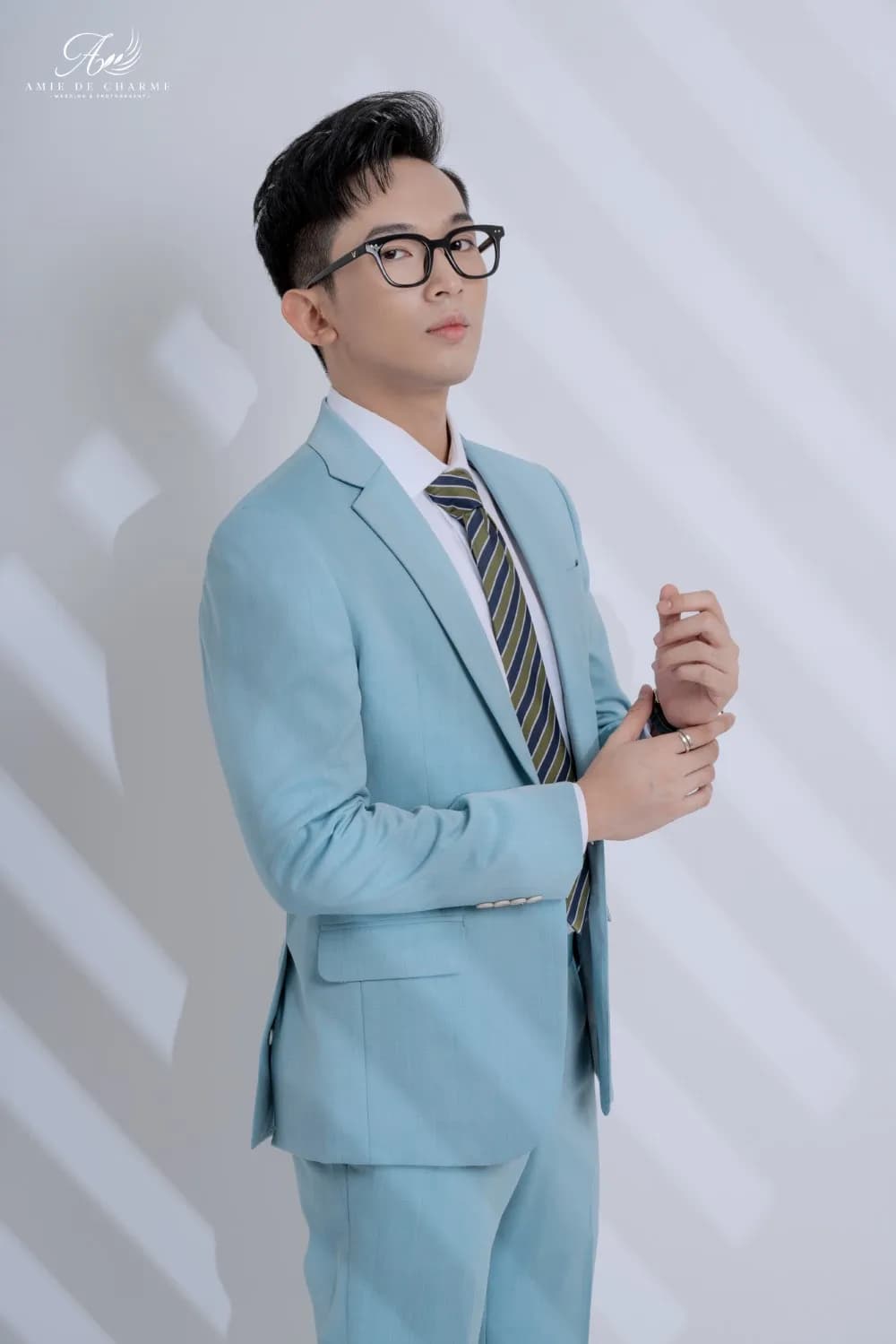Suit xanh ngọc nhạt, chỉnh khuy măng sét, nhìn nghiêng