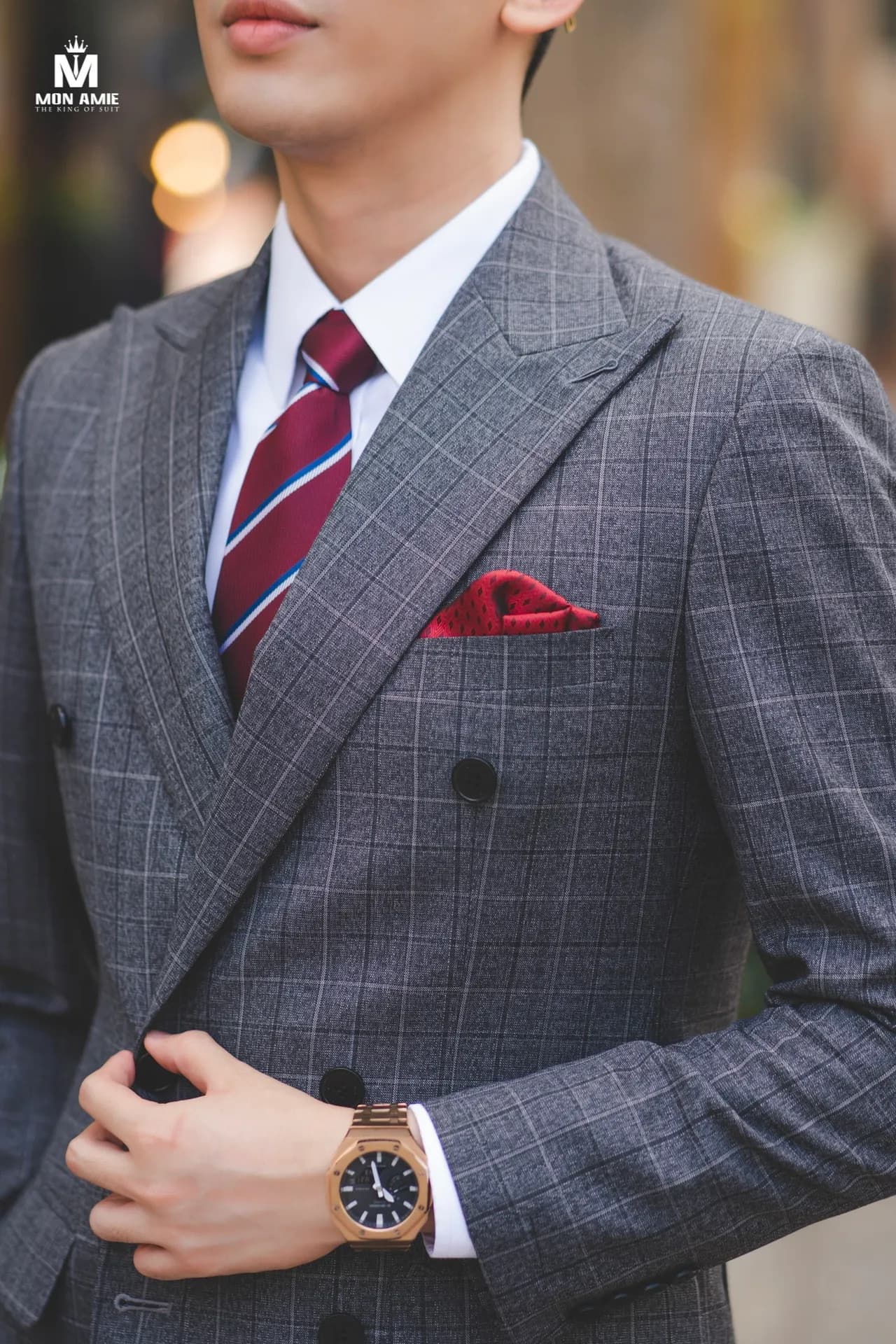 Cận cảnh ve áo suit xám caro, cà vạt sọc đỏ, khăn cài túi, đồng hồ