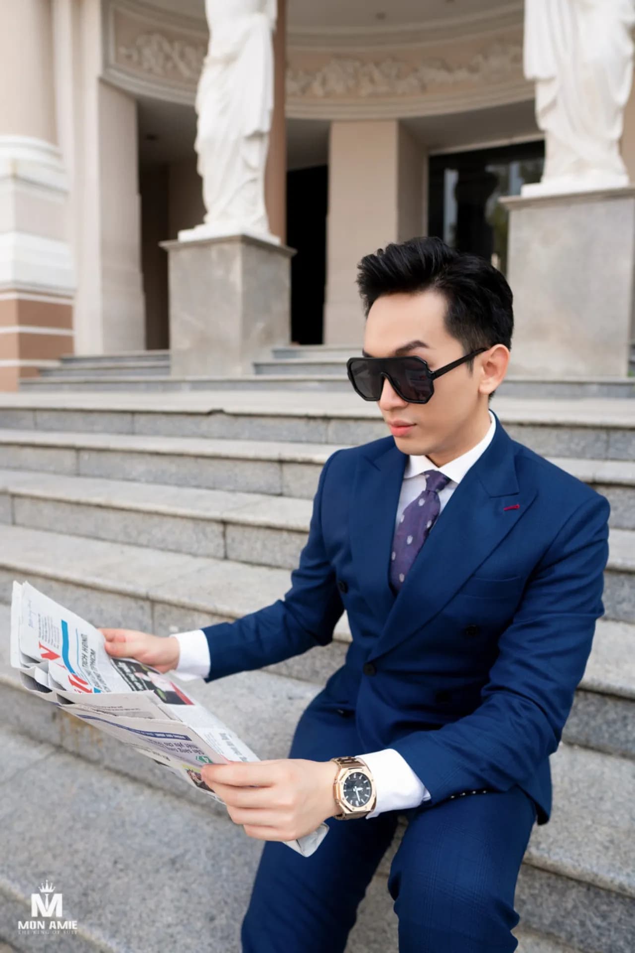 Suit xanh royal hai hàng khuy ngồi bậc thềm, đọc báo, kính râm