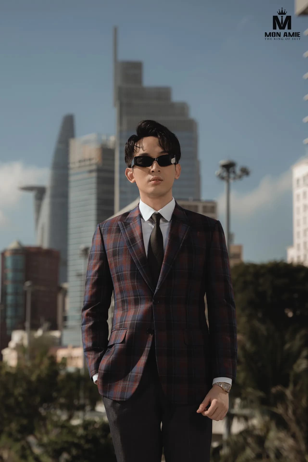 Suit caro tím đô cận cảnh, cà vạt đen, nền tòa nhà chọc trời