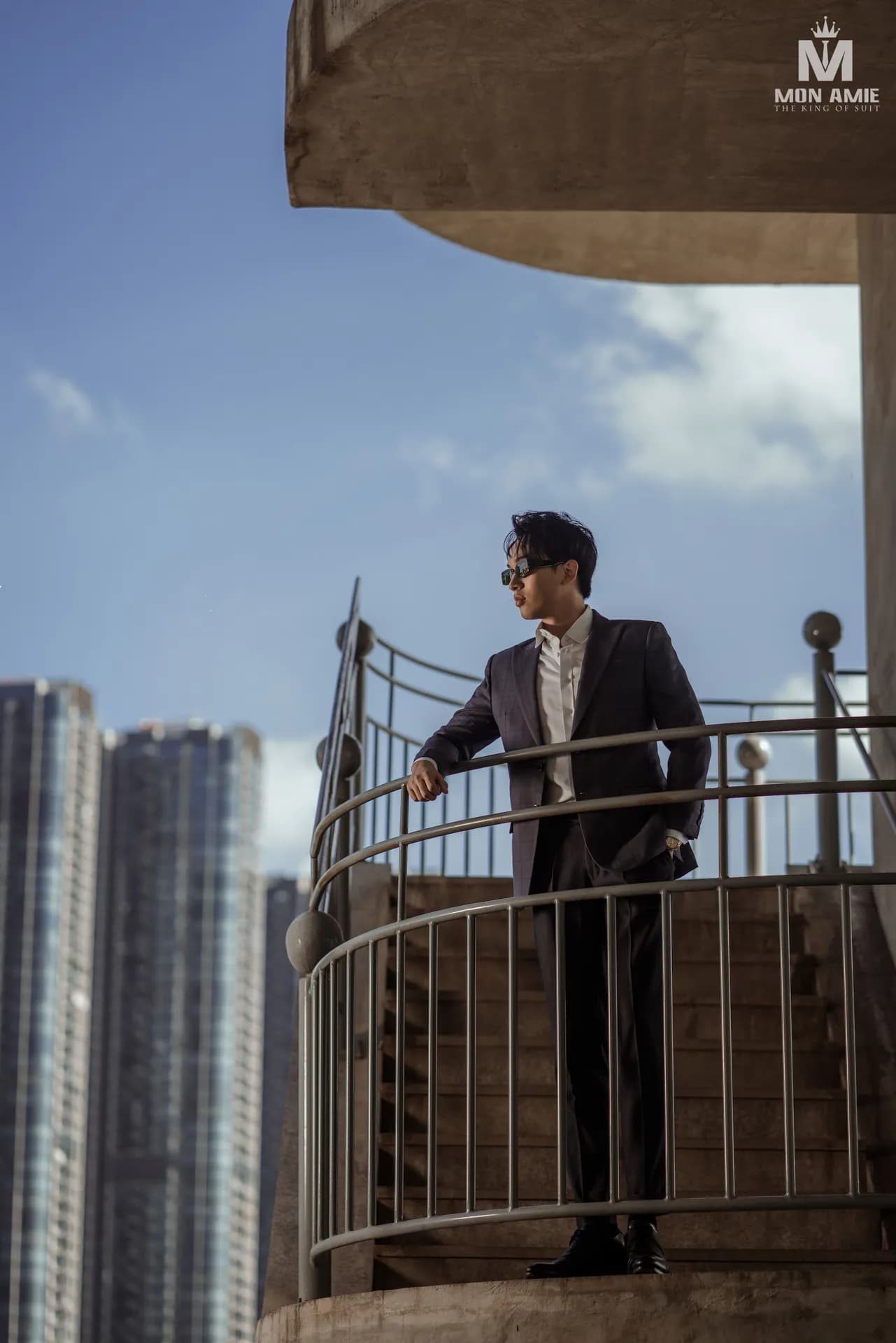 Suit tối màu tựa lan can cầu thang xoắn, nền tòa nhà cao tầng