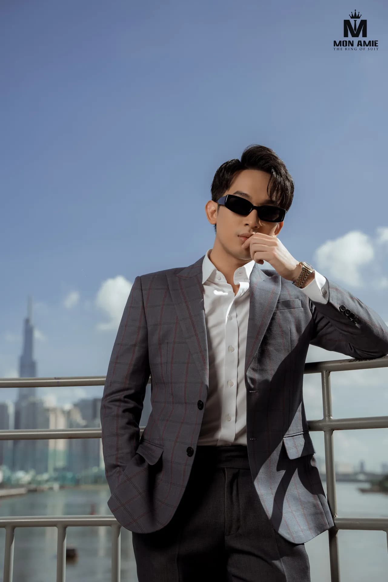 Blazer xám, kính râm, ngước nhìn góc thấp, nền trời xanh và bờ sông