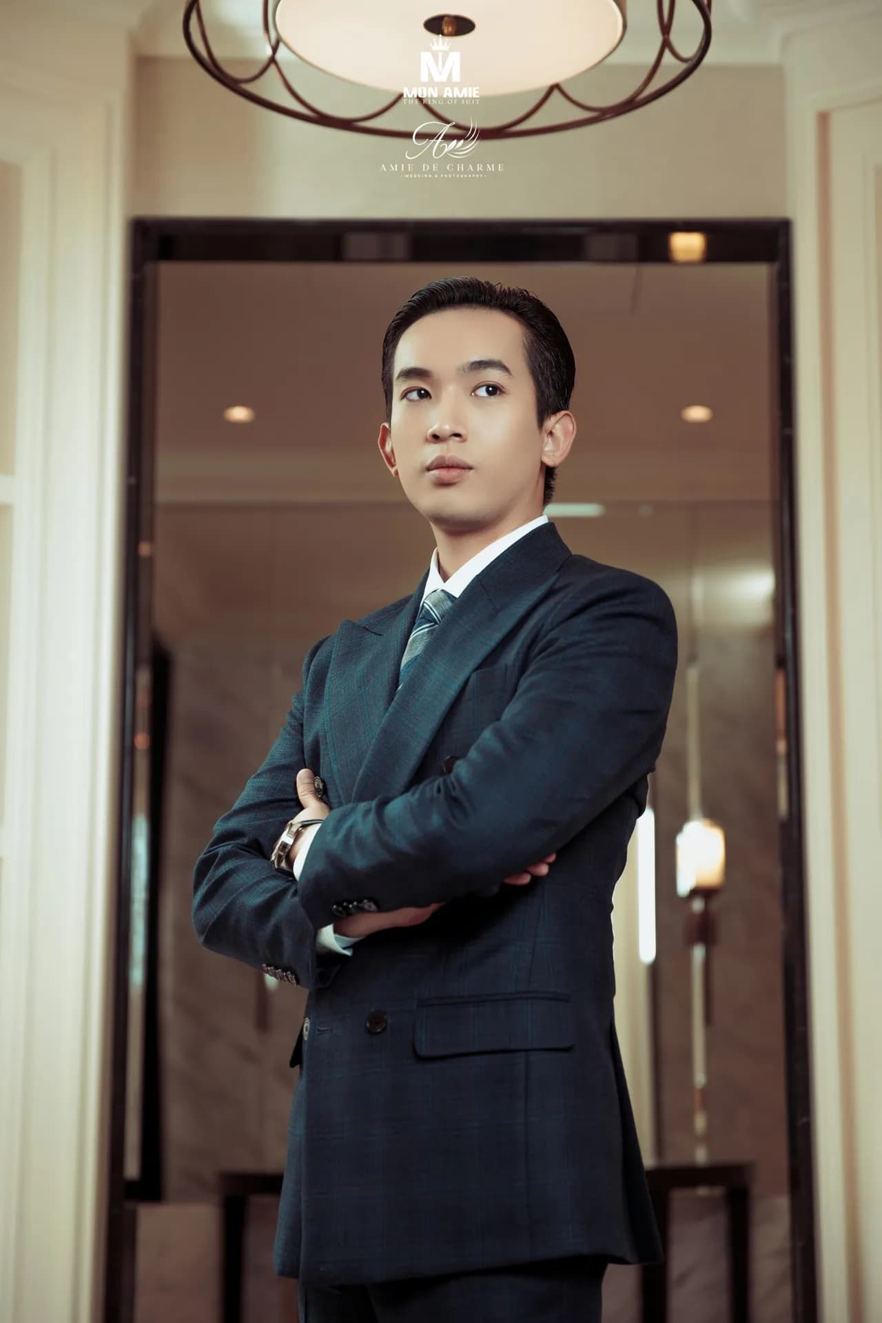 Suit navy cài hai hàng, khoanh tay dưới đèn trần, góc chụp từ dưới lên
