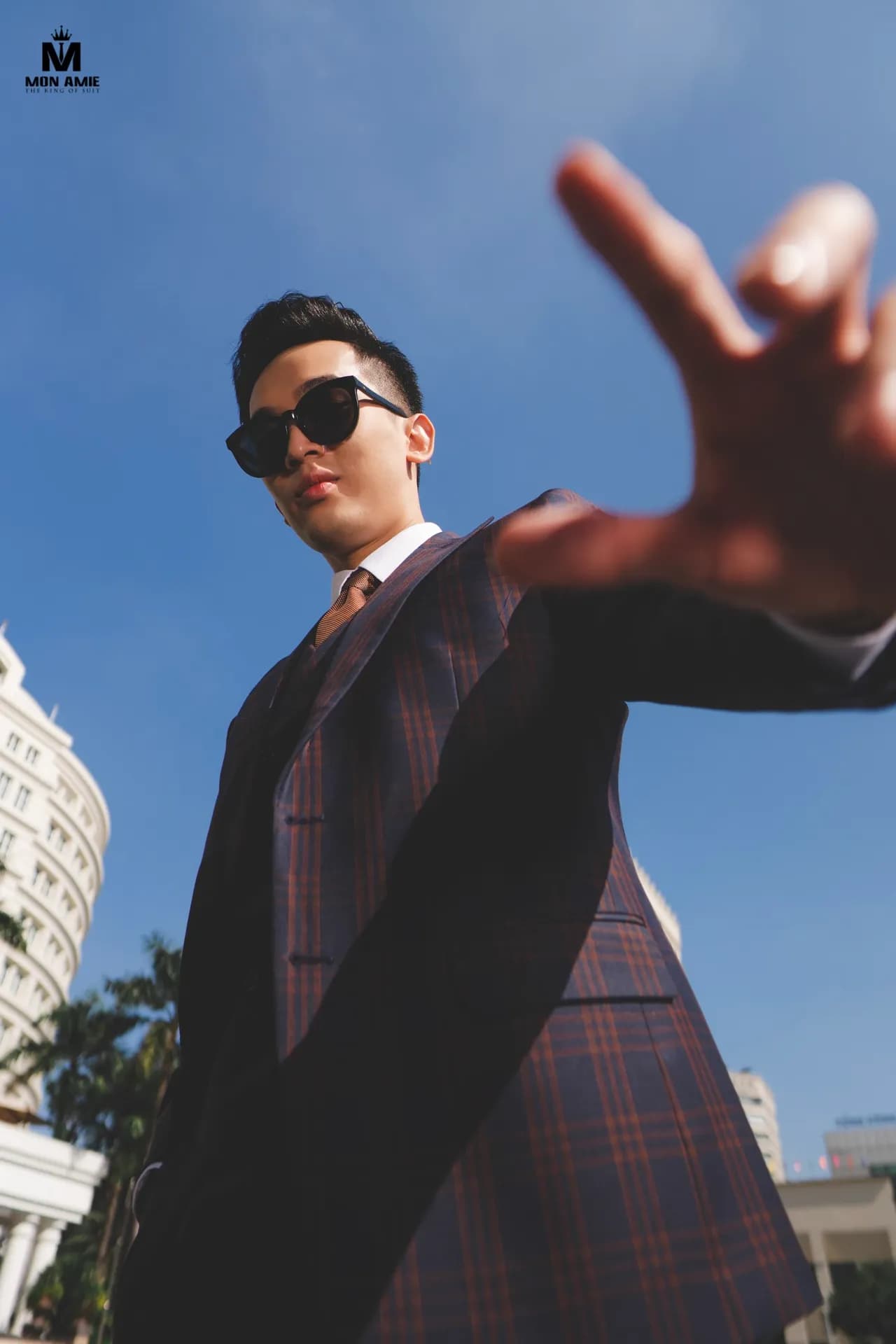Suit caro tím, kính râm, đưa tay hướng ống kính góc rộng sáng tạo