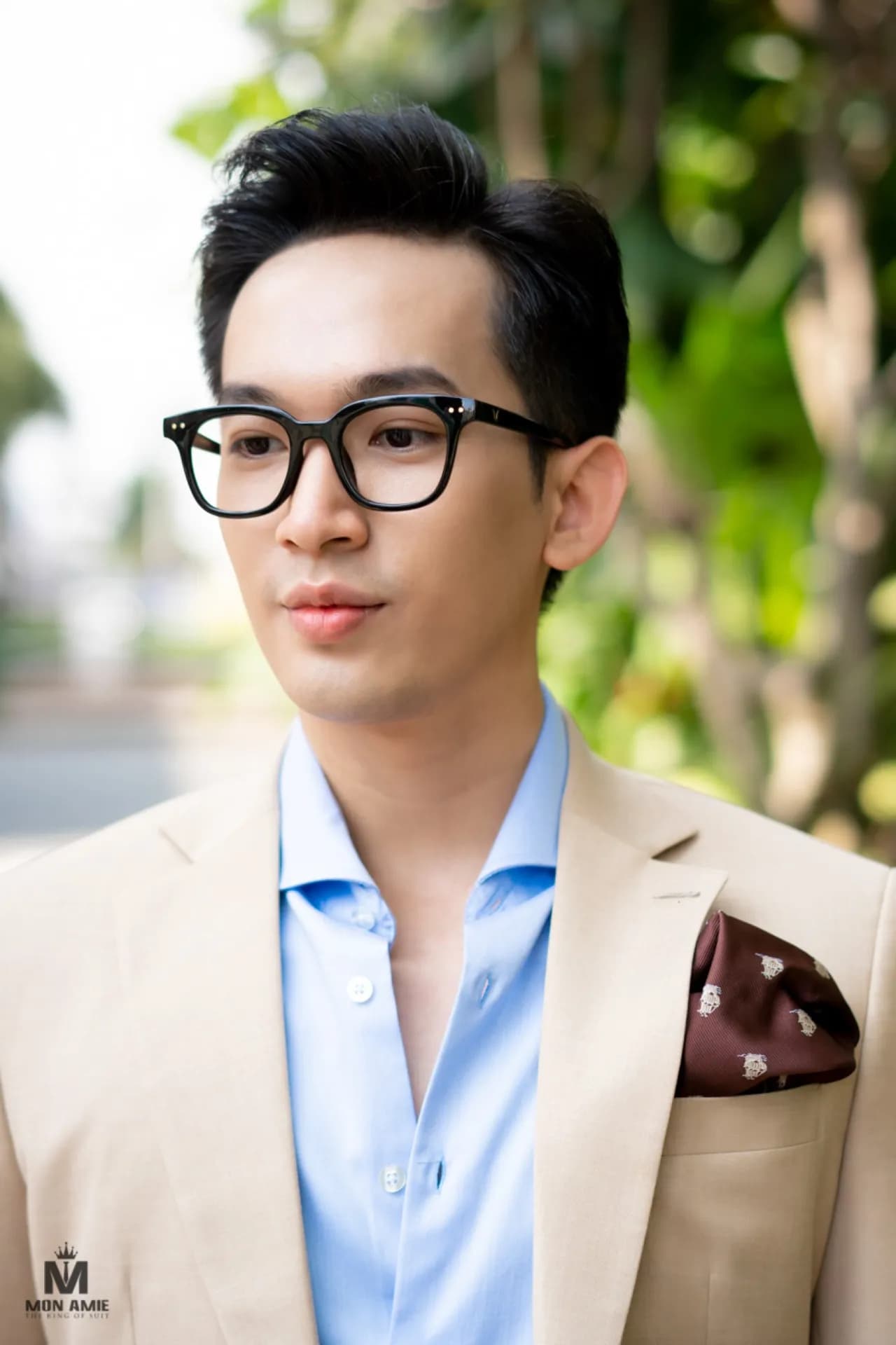 Cận cảnh blazer be, sơ mi xanh nhạt hở cổ, khăn cài túi nâu, kính cận