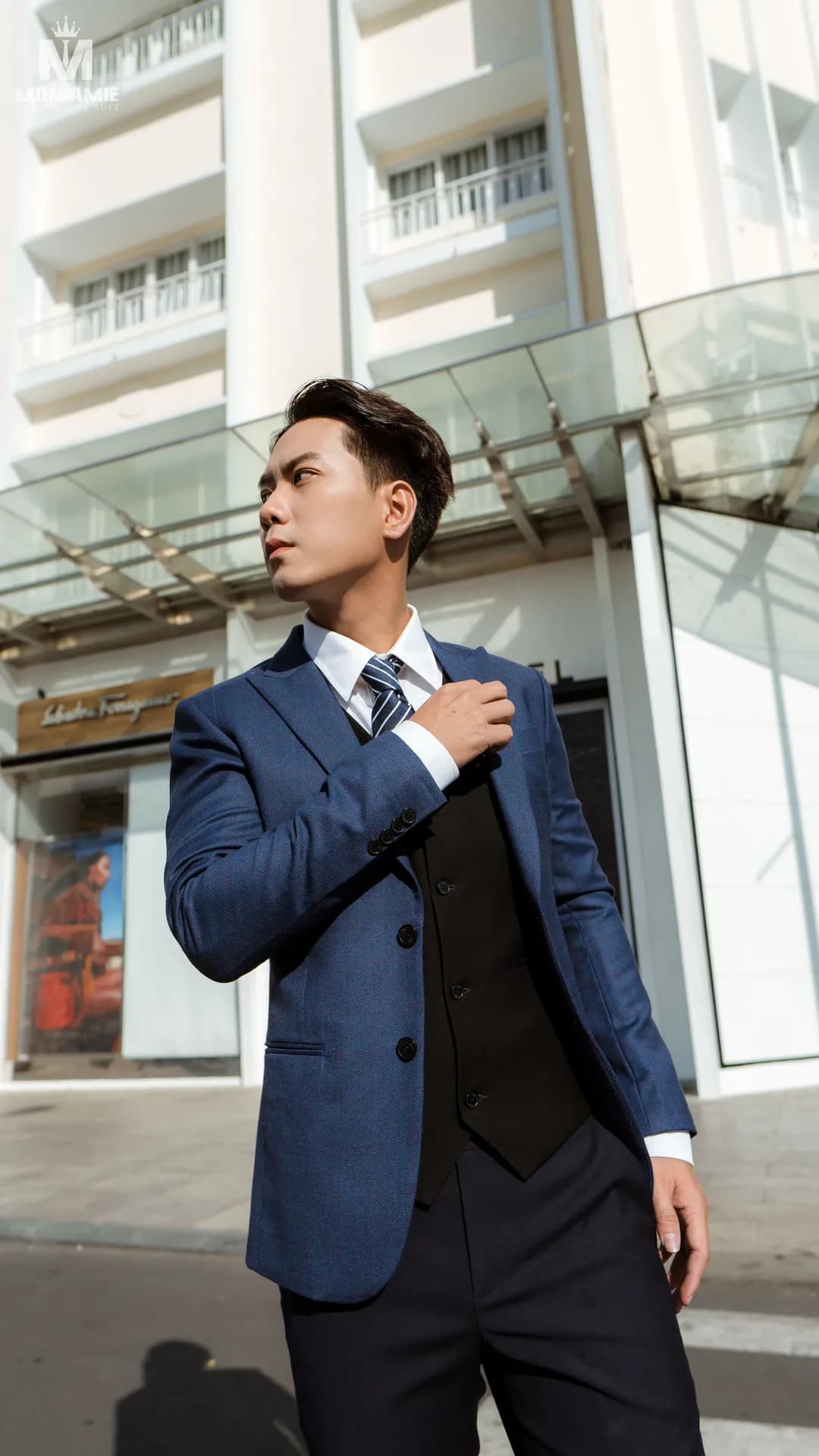 Vest xanh navy, gile đen, cà vạt kẻ sọc, chỉnh cổ áo trên phố