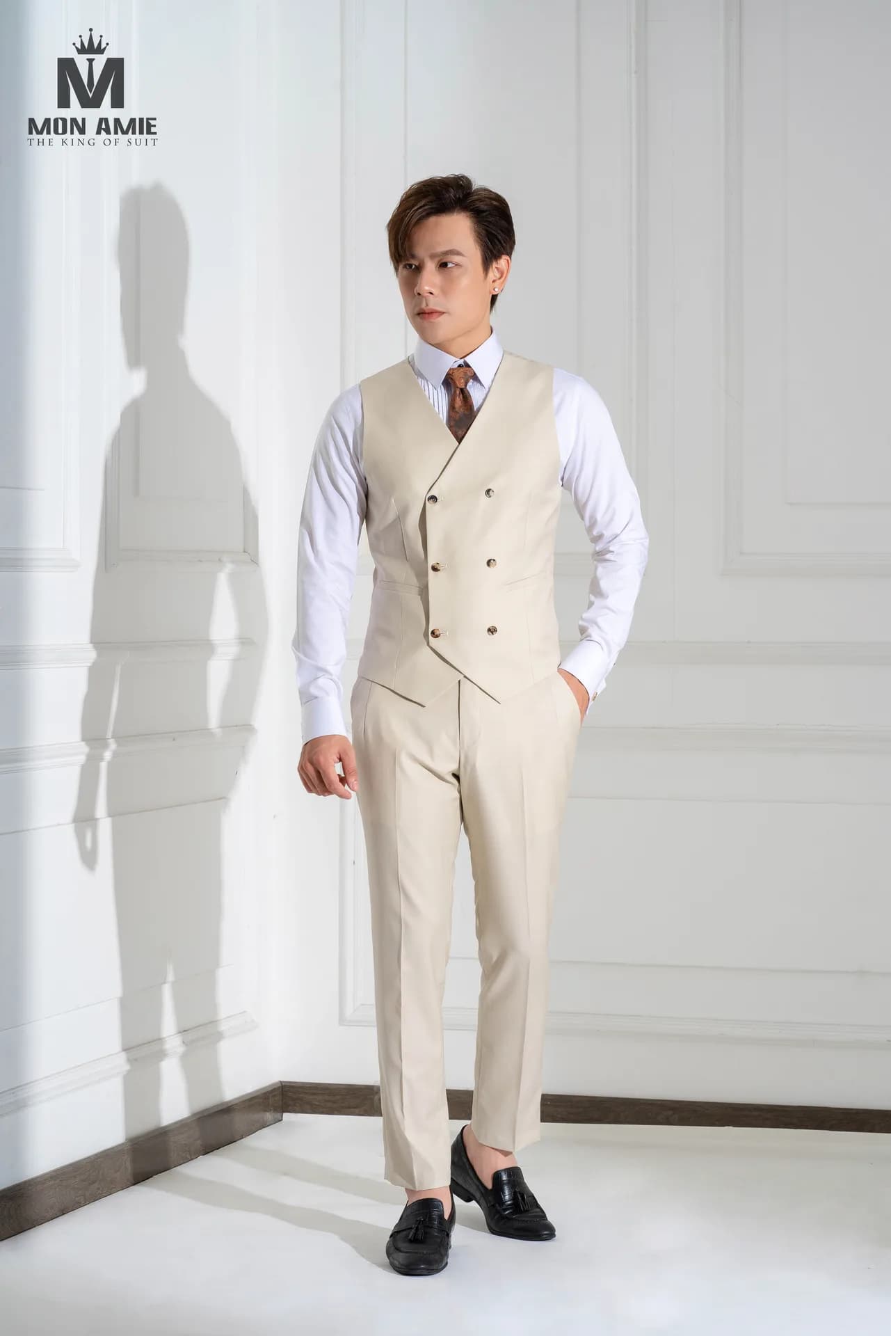 Gilet hai hàng khuy phối quần be kem, sơ mi trắng và cà vạt nâu.