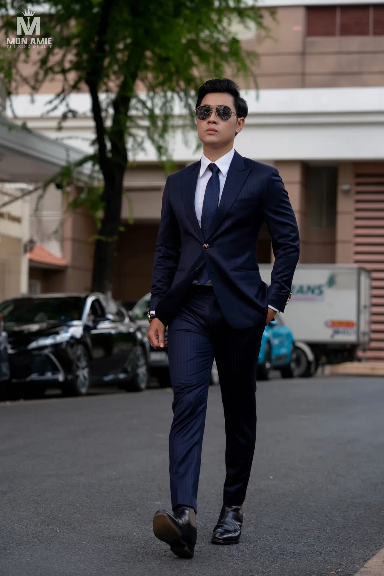 Suit xanh navy kẻ sọc, kính râm, dáng đi tự tin trên phố