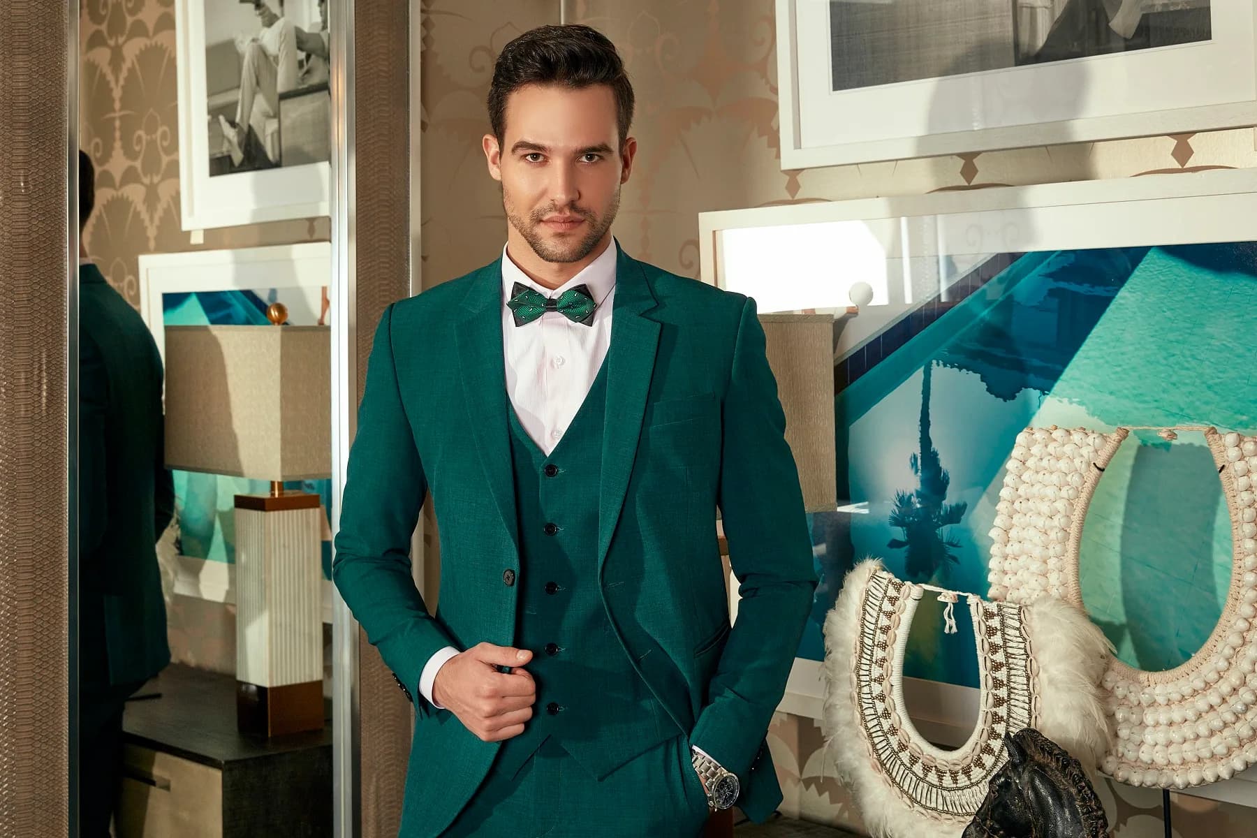 Suit ba mảnh xanh lục bảo, nơ xanh cùng tông, tay đút túi quần