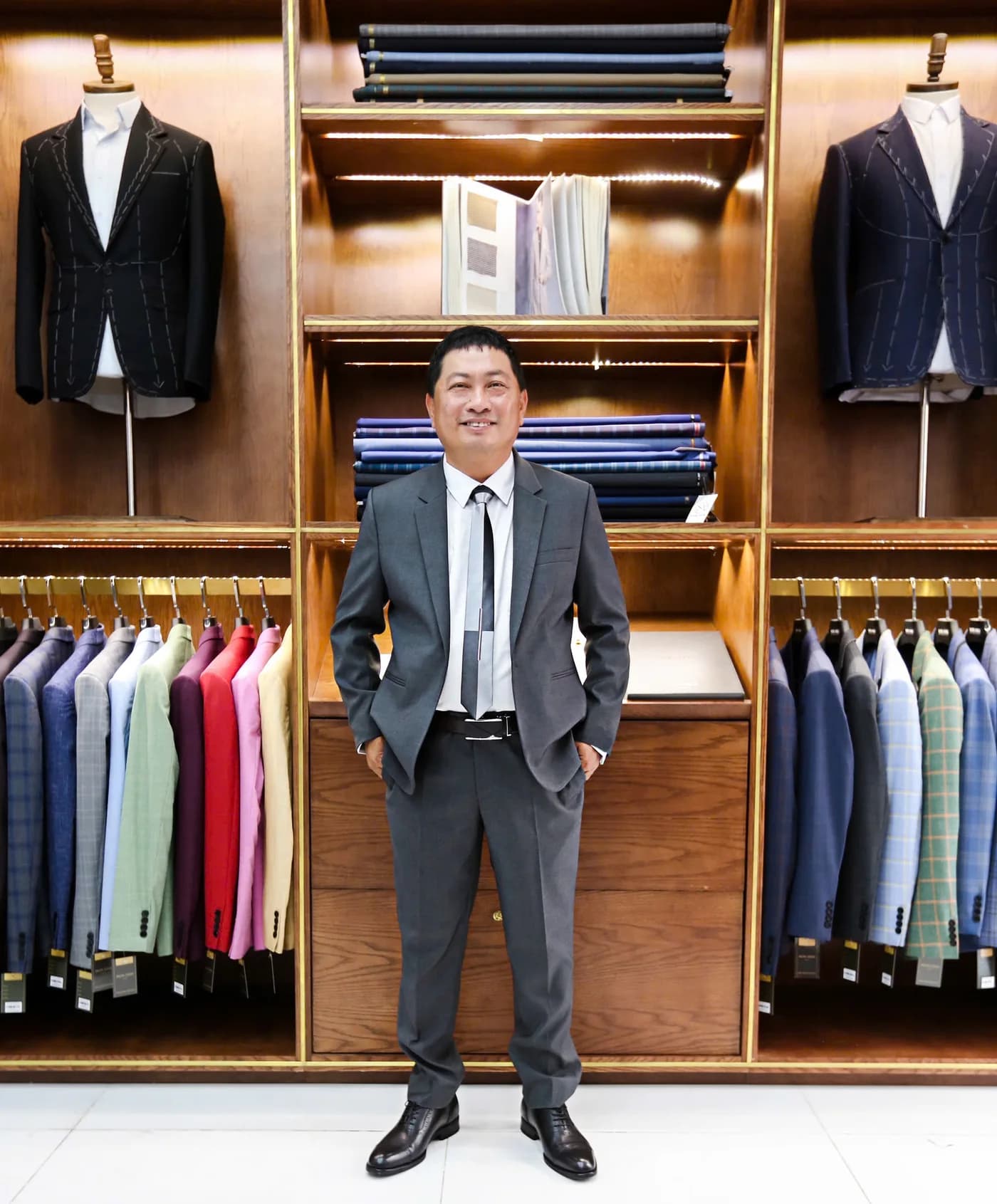 Quý ông vest xám ghi, cà vạt đen, cửa hàng vải cao cấp