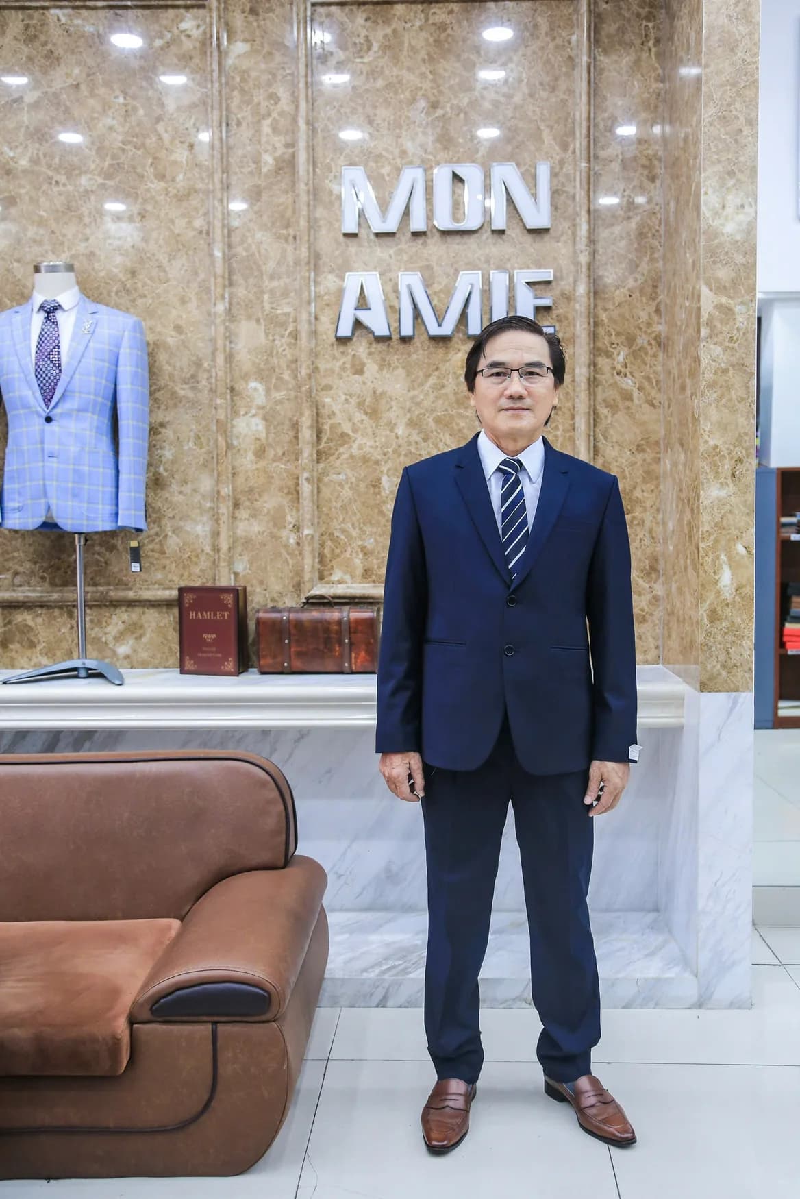 Quý ông vest navy đứng trước bảng hiệu Mon Amie