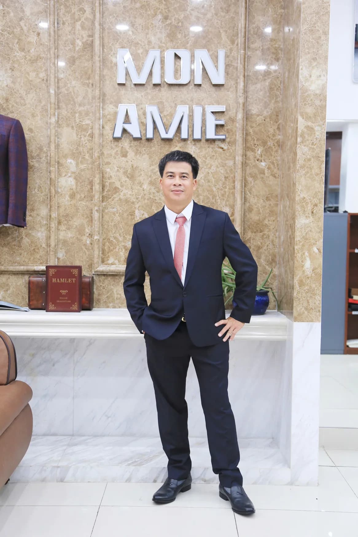 Người đàn ông vest navy, cà vạt đỏ, tay chống hông