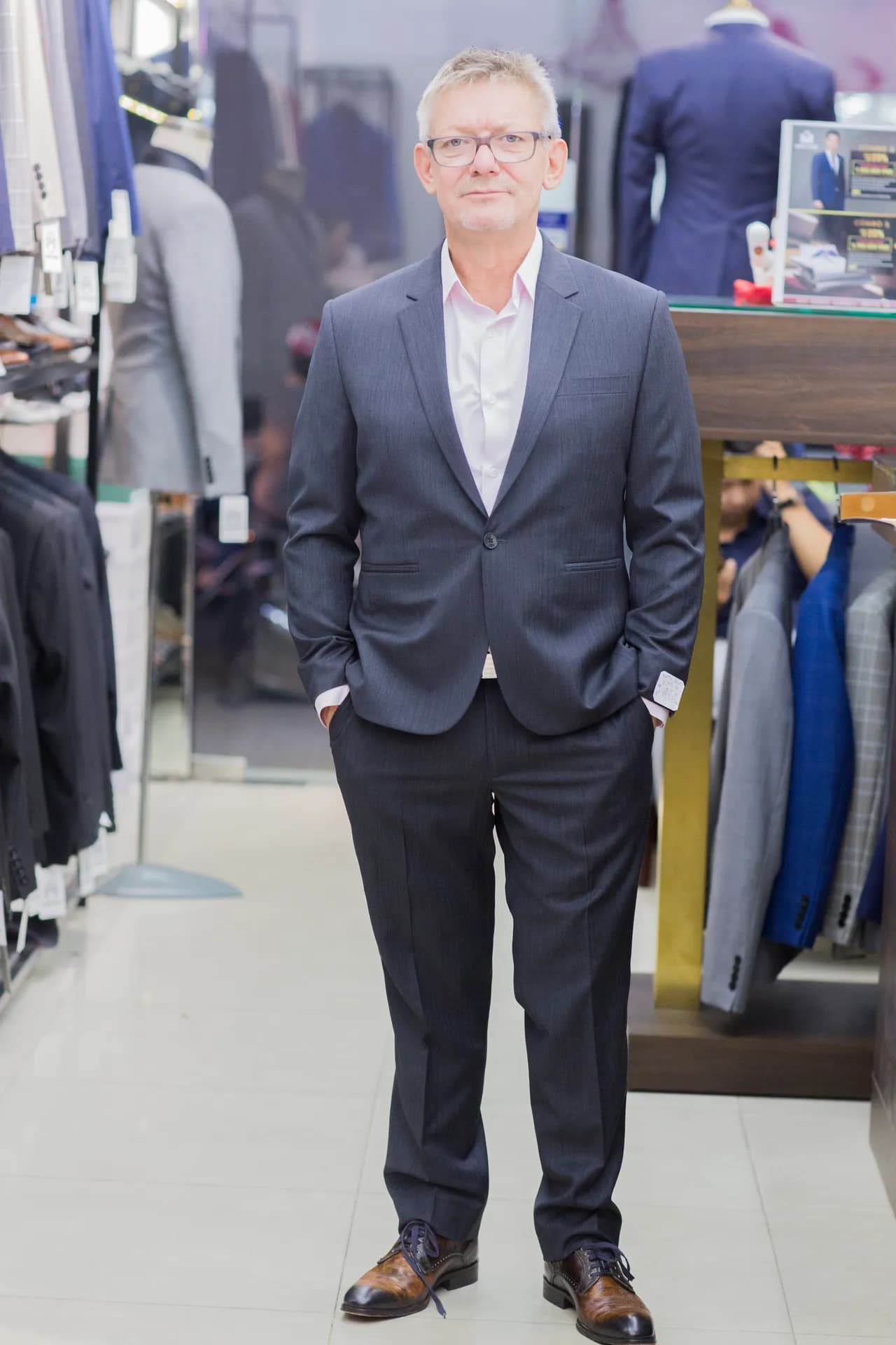 Suit xám than một cúc, sơ mi hồng nhạt và kính gọng xám, phong cách phóng khoáng