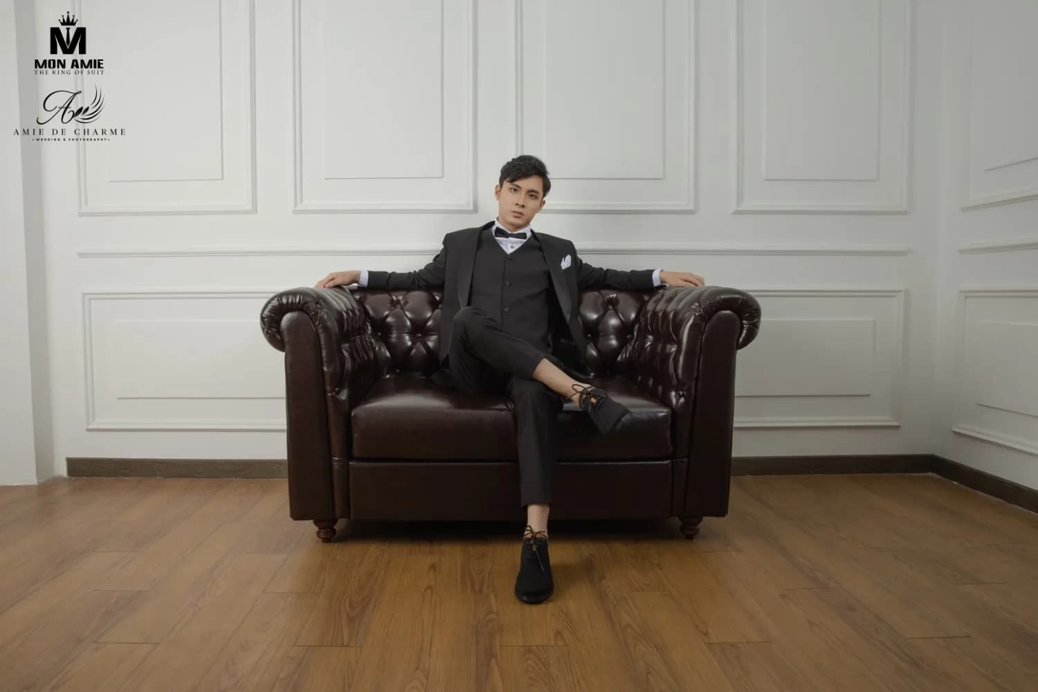Tuxedo đen thả lỏng trên ghế sofa Chesterfield, sàn gỗ ấm
