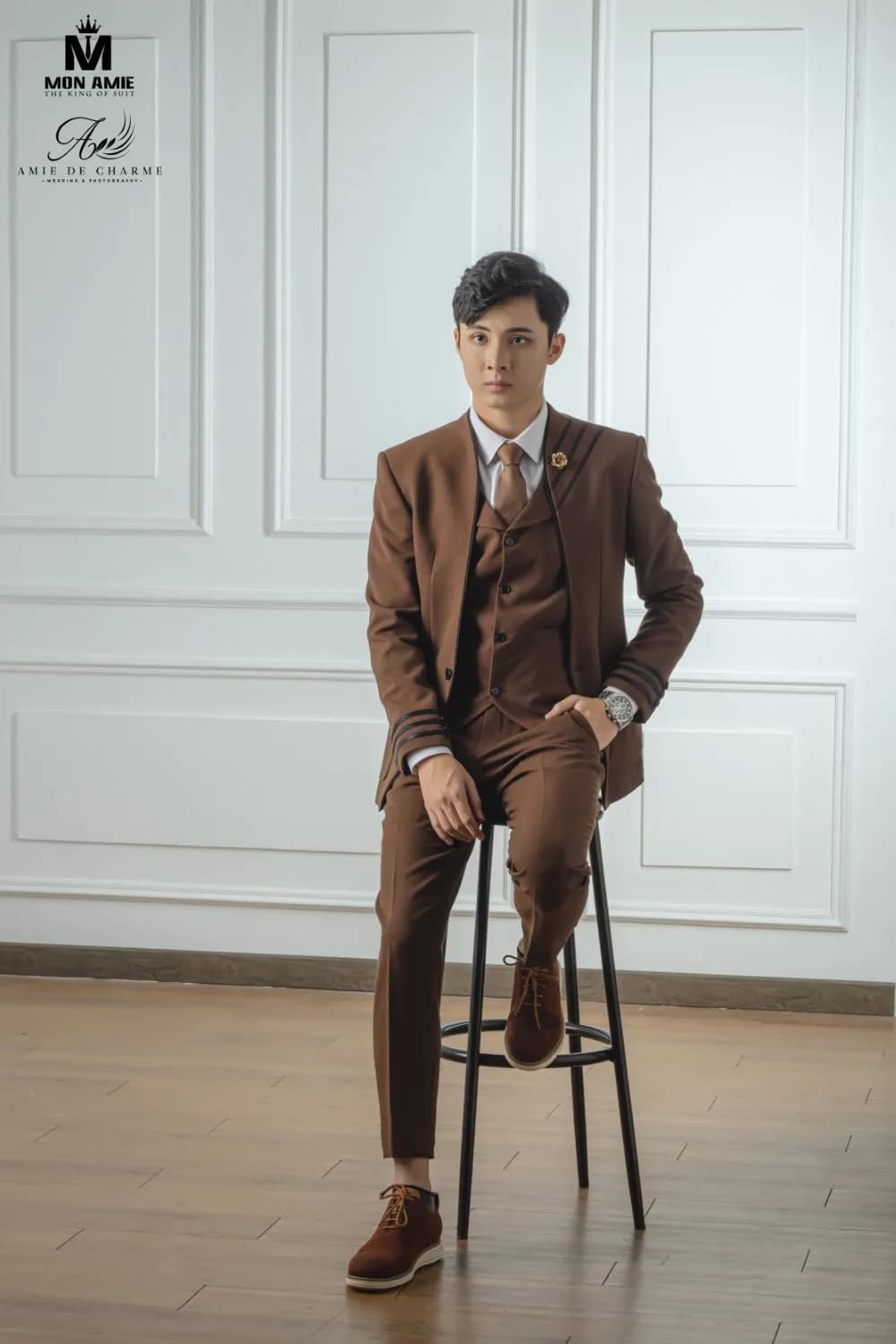 Suit ba mảnh nâu, ngồi ghế cao, giày da nâu, sàn gỗ