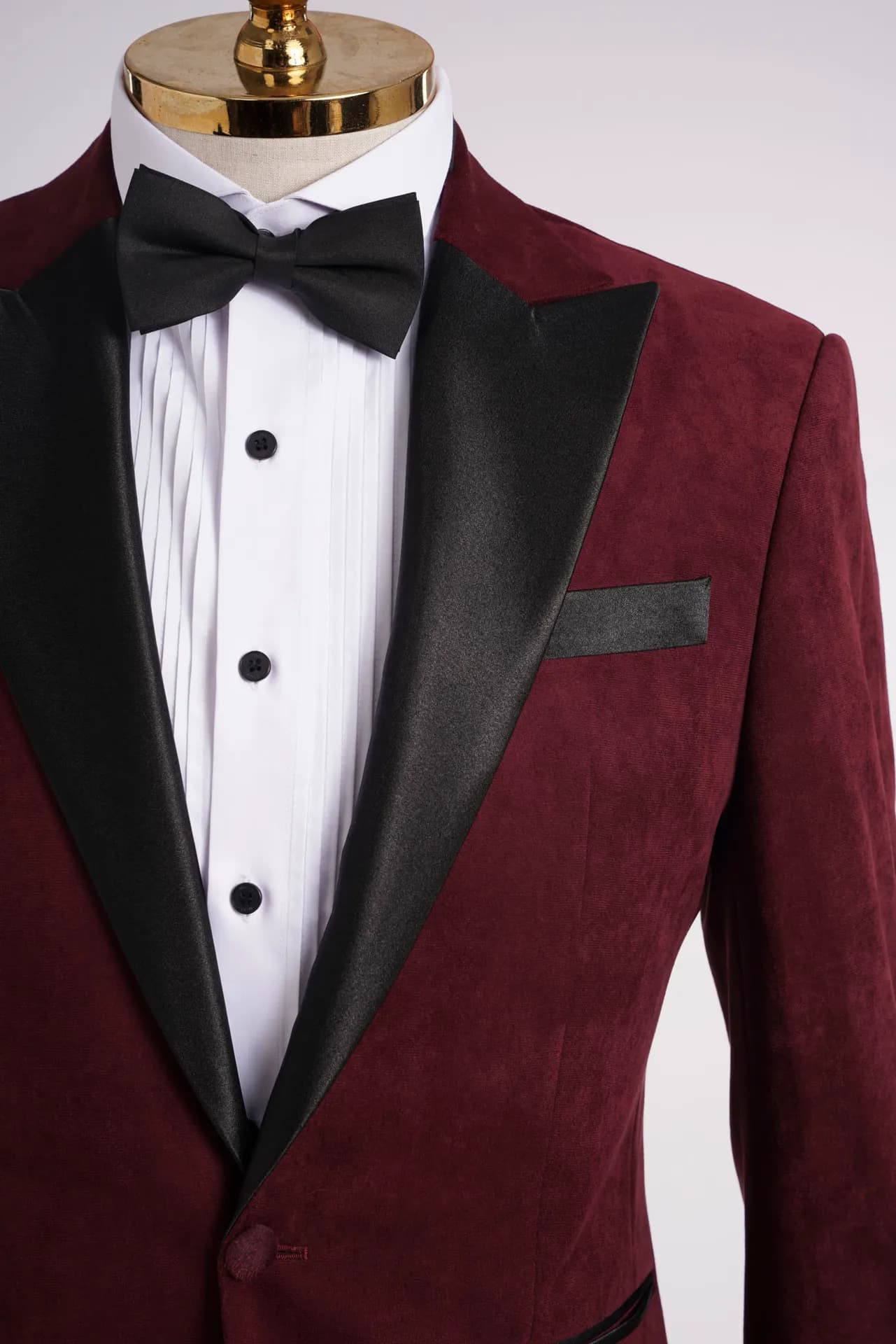 Cận cảnh cổ ve satin đen của tuxedo nhung đỏ đô, sơ mi trắng và nơ đen