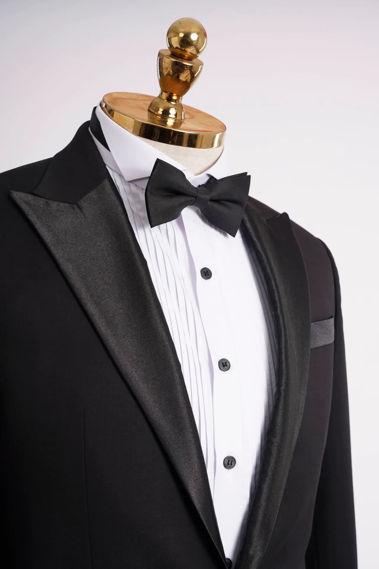 Cận cảnh ve nhọn tuxedo đen, sơ mi trắng cài khuy đen và nơ