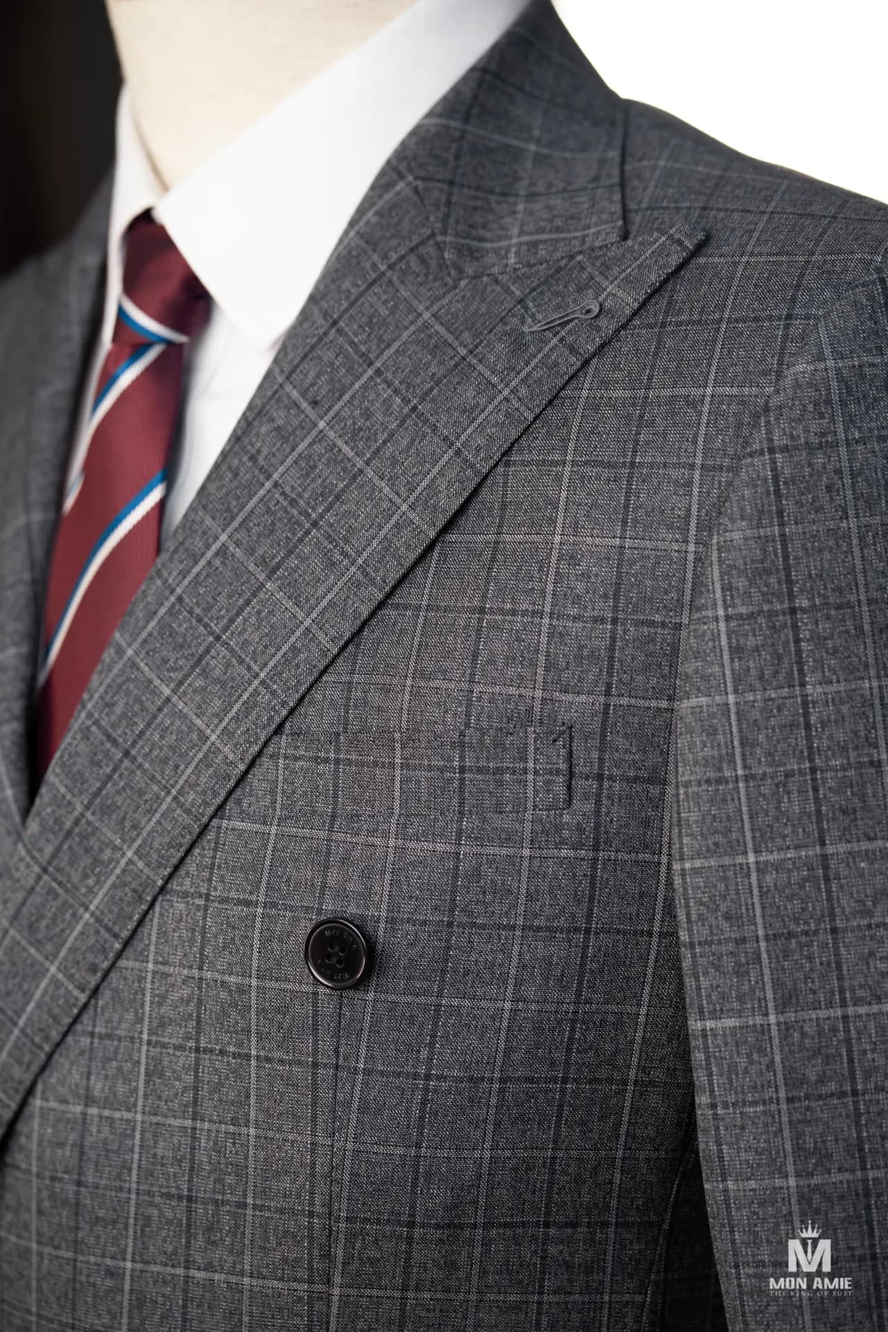Cận cảnh suit xám ca-rô hai hàng, ve nhọn và cà vạt sọc đỏ xanh