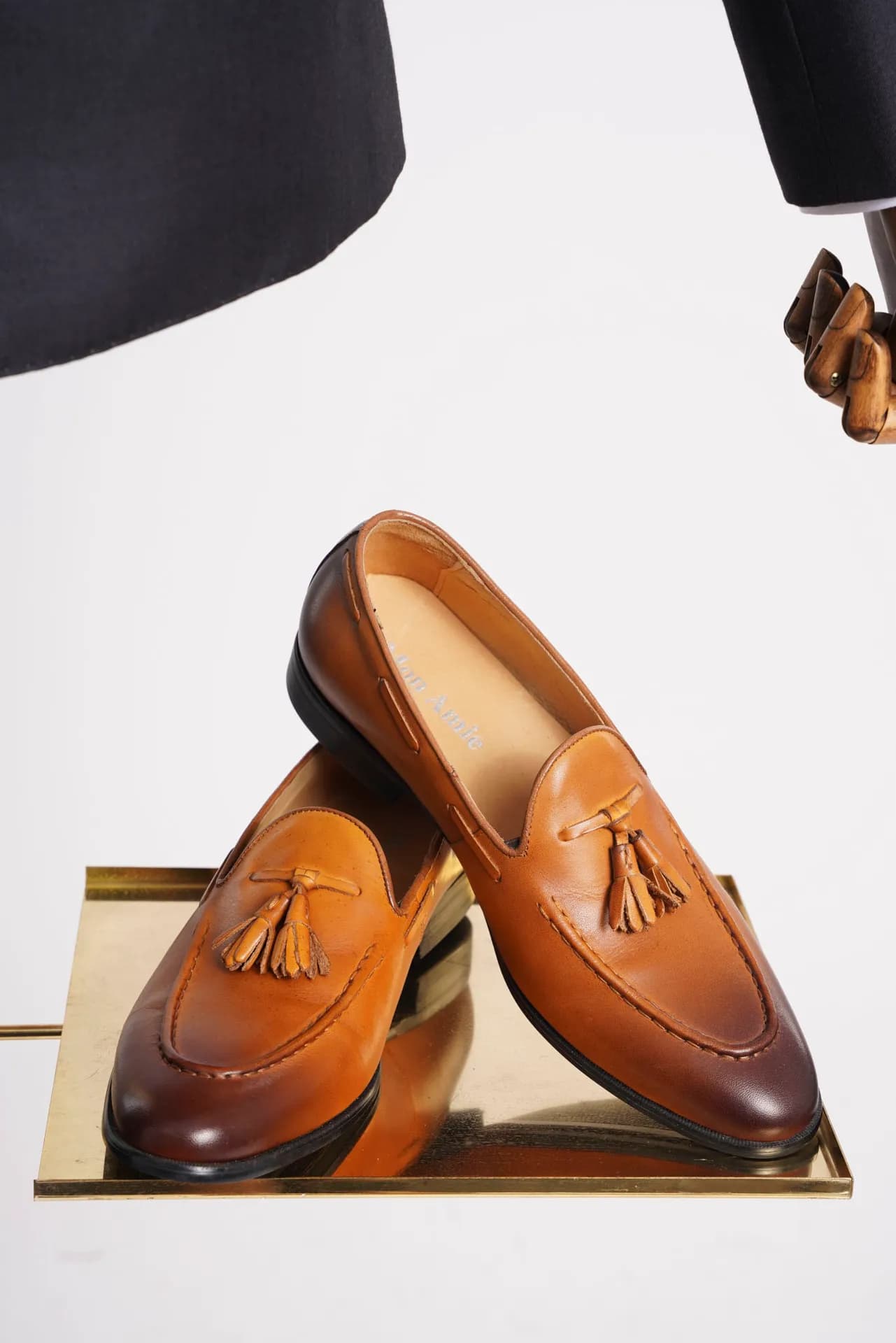 Giày loafer da nâu tassel trên bệ vàng, phụ kiện đi kèm bộ suit