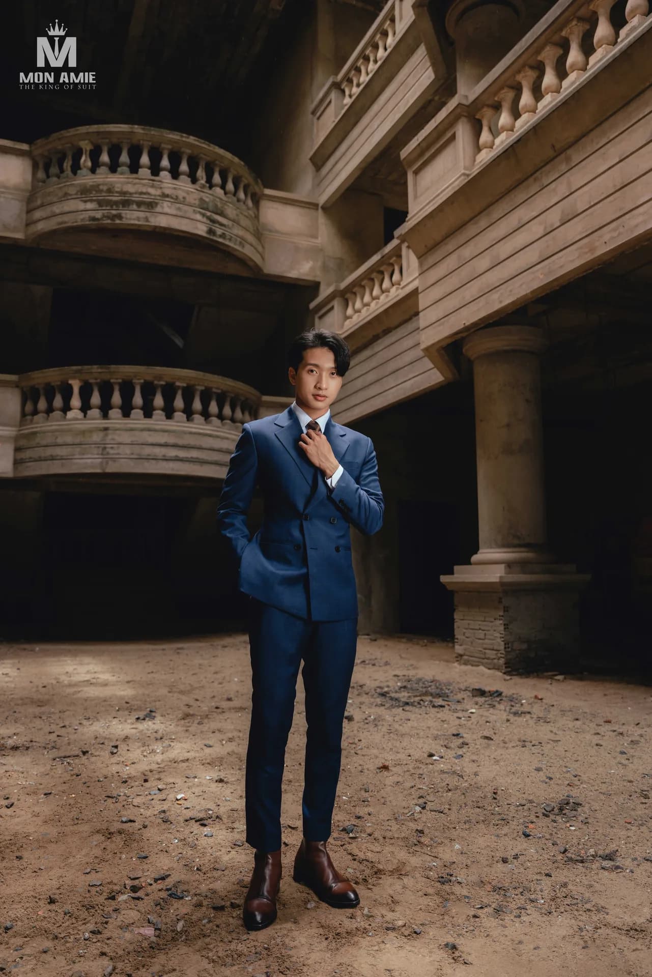 Suit xanh navy hai hàng khuy giữa kiến trúc cổ với ban công cột tròn