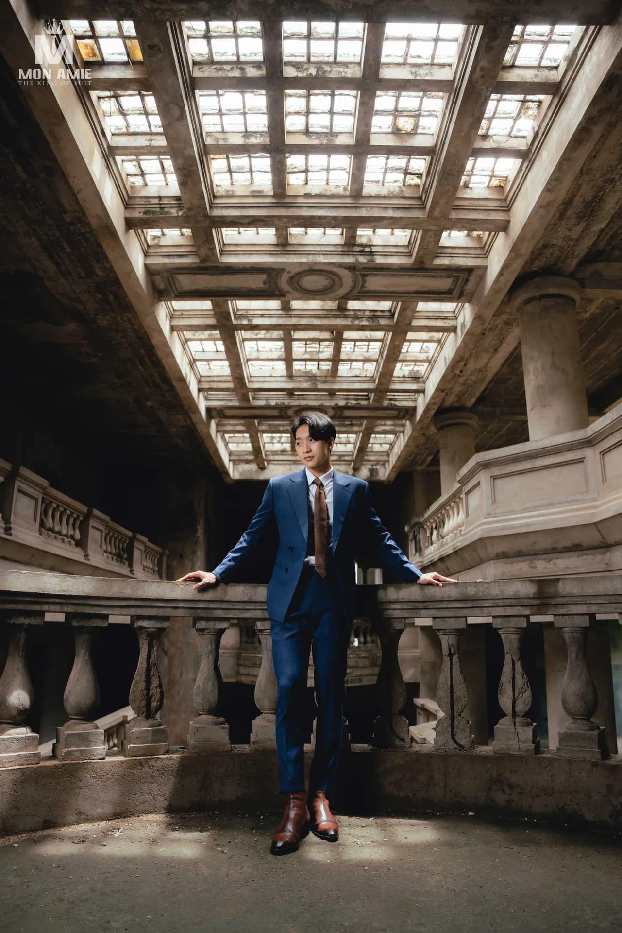 Suit xanh navy dưới giếng trời cổ, tay chống lan can con tiện
