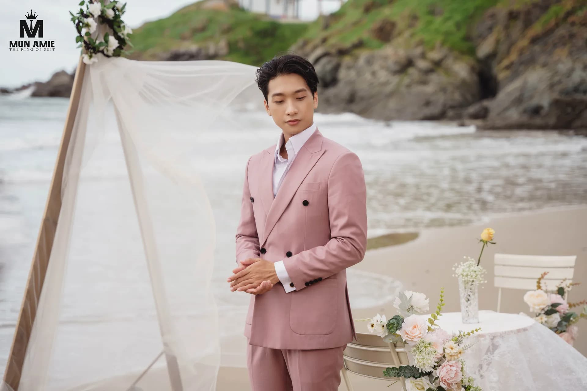 Suit hồng hai hàng khuy, dáng đứng trầm lặng bên cổng voan và bàn hoa