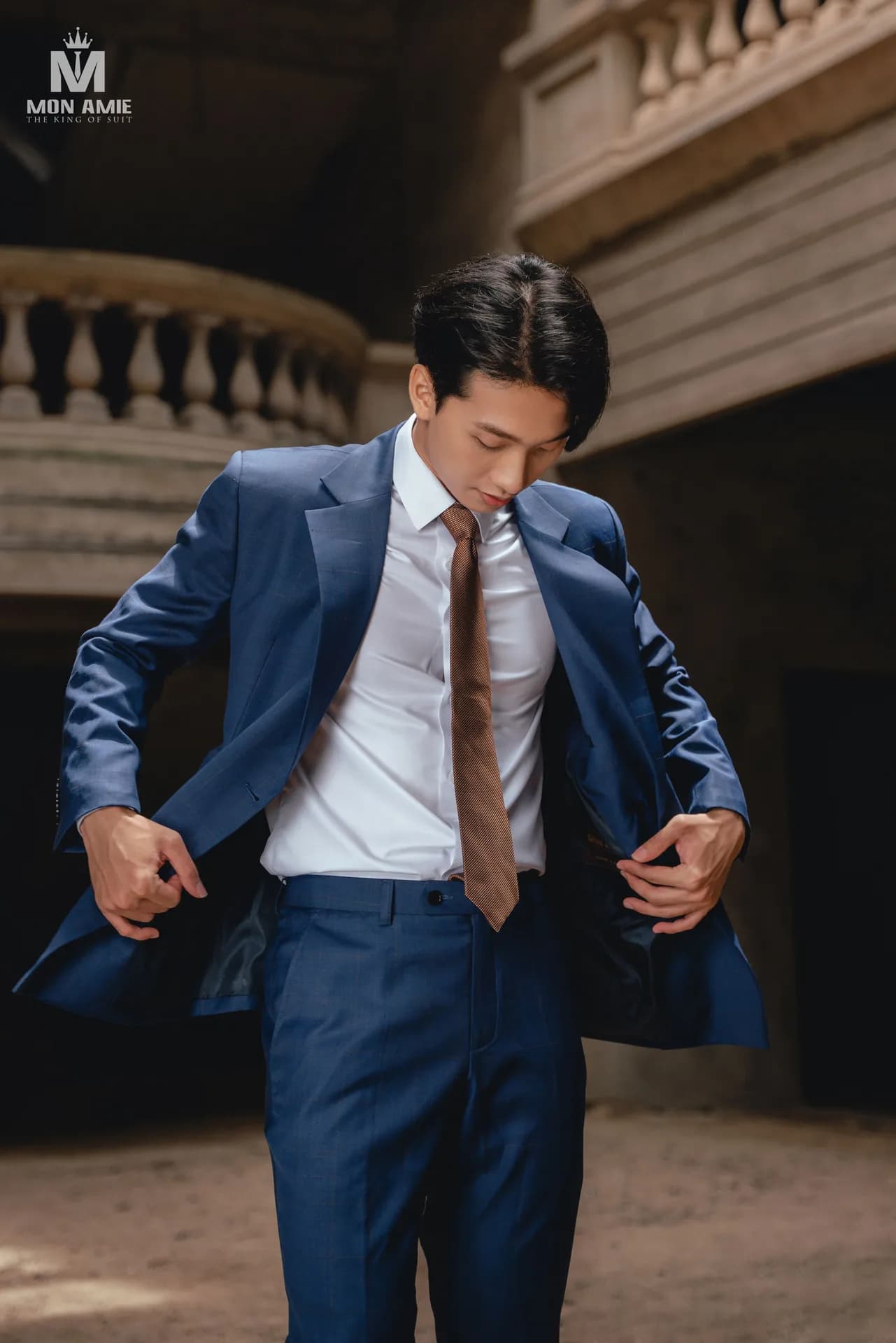 Khoảnh khắc chỉnh vạt áo suit xanh navy, cà vạt nâu nổi bật