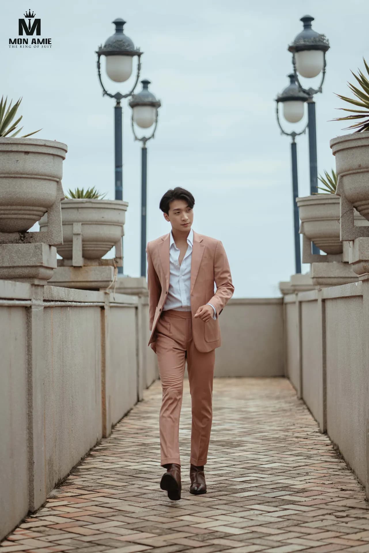 Suit hồng đất sải bước trên lối đi lát gạch giữa hai hàng đèn cổ