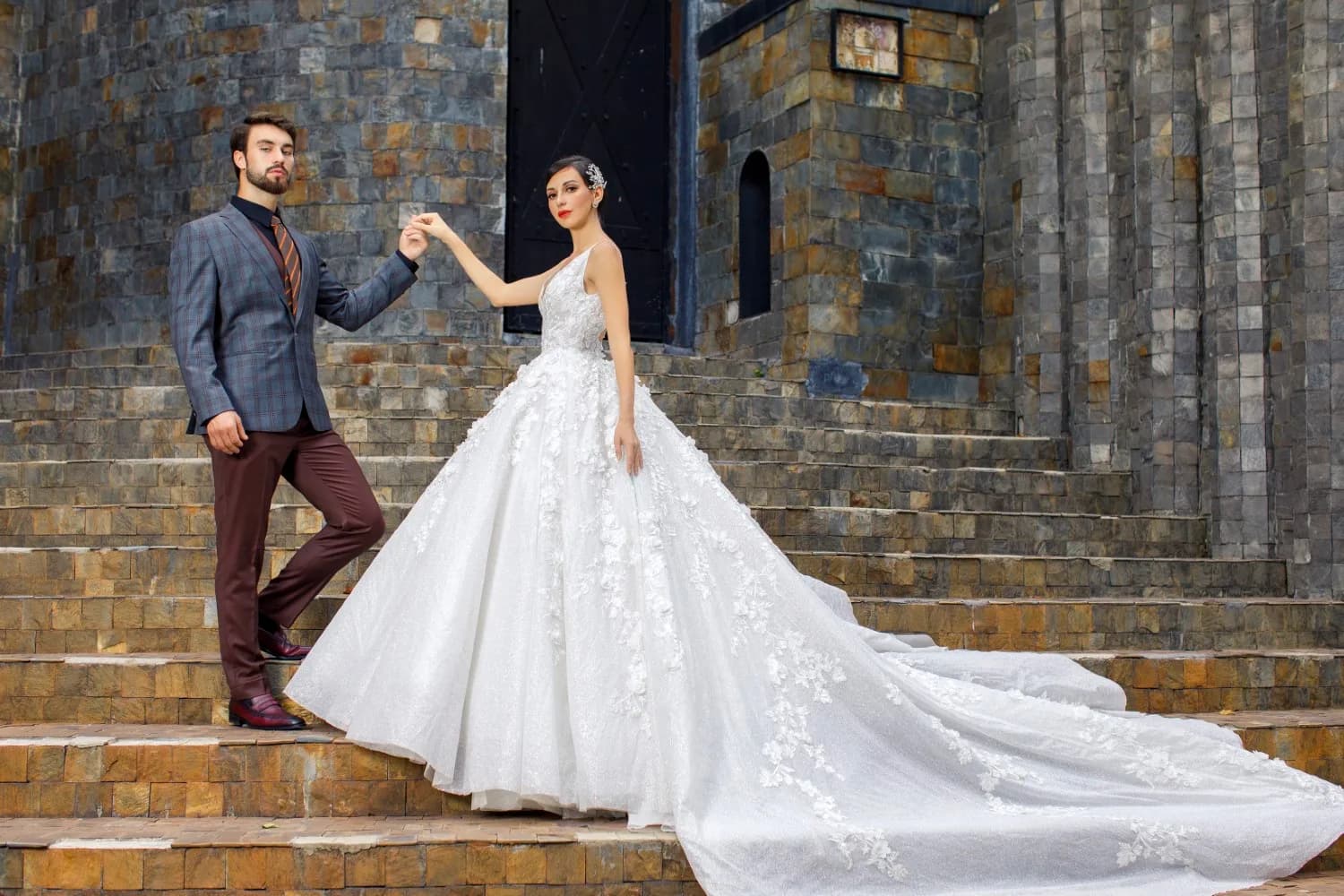Suit tối màu và váy cưới đuôi dài trên bậc thang đá