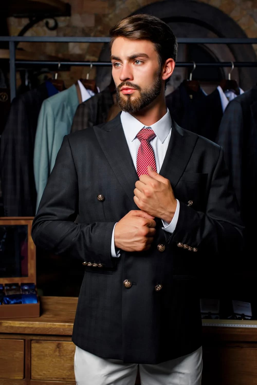Cận cảnh blazer đen hai hàng khuy đồng chạm nổi, cà vạt sọc đỏ