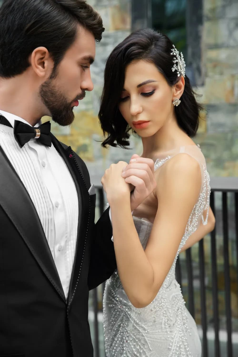 Chú rể tuxedo thắt nơ bên cô dâu váy đính hạt, cận cảnh lãng mạn