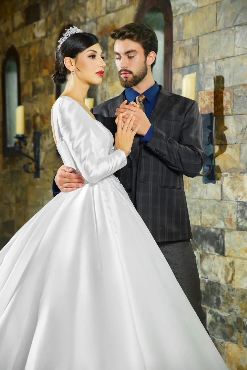 Chú rể suit kẻ ô xám khoác tay cô dâu váy satin dài tay trong sảnh đá