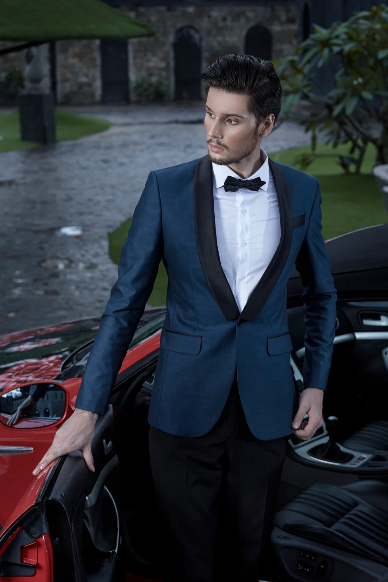 Tuxedo xanh navy ve nhung, nơ đen, tựa cửa xe thể thao đỏ ngày mưa