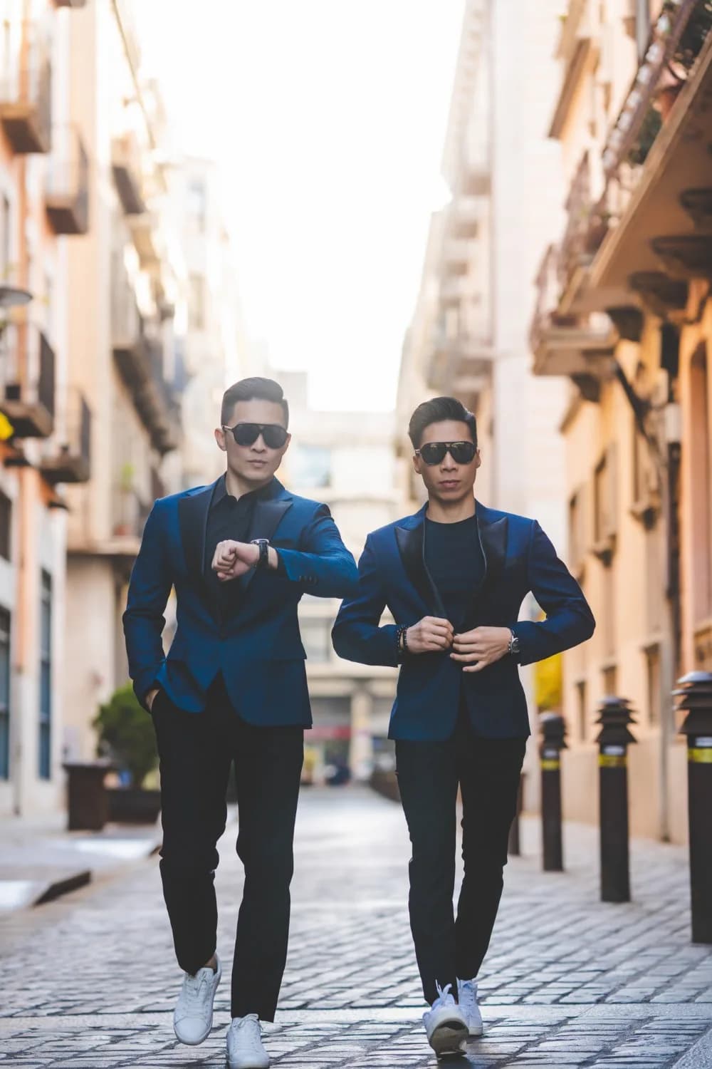 Suit caro xanh xám phối gile nâu đỏ, đặt tay lên hộp phụ kiện trên bàn may