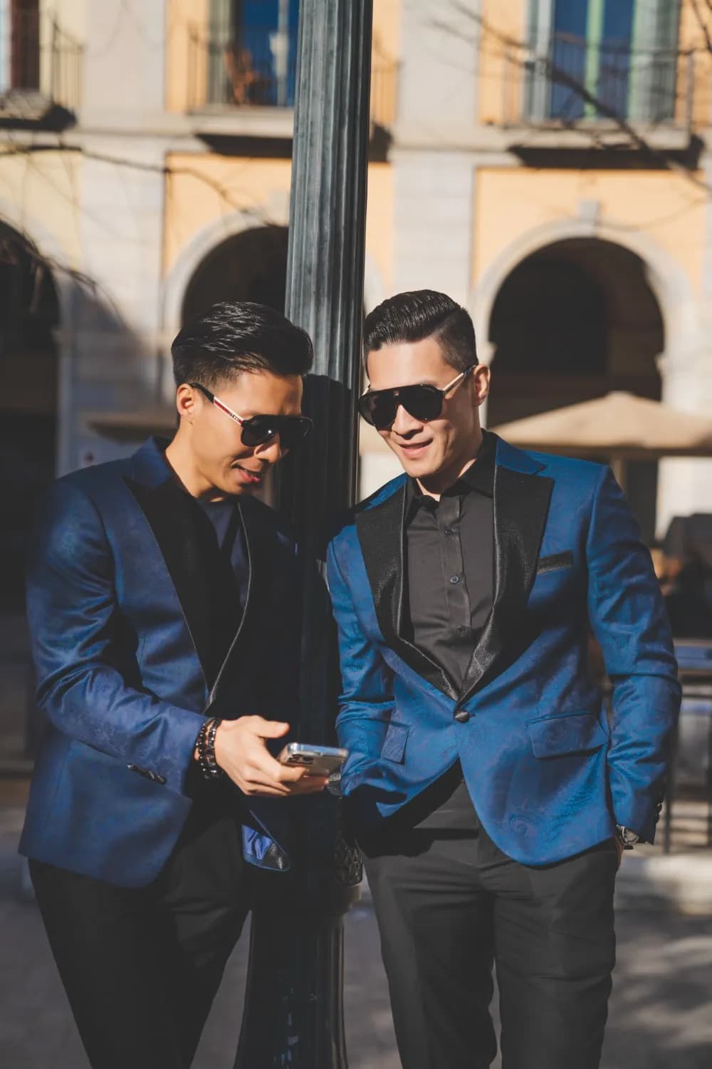 Hai blazer xanh sapphire hoa văn paisley cổ ve đen, trò chuyện bên cột đèn
