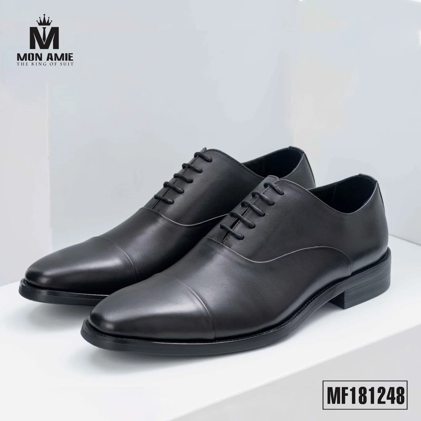 Glossy black cap-toe oxford shoes with a black sole, a formal groom's shoe style