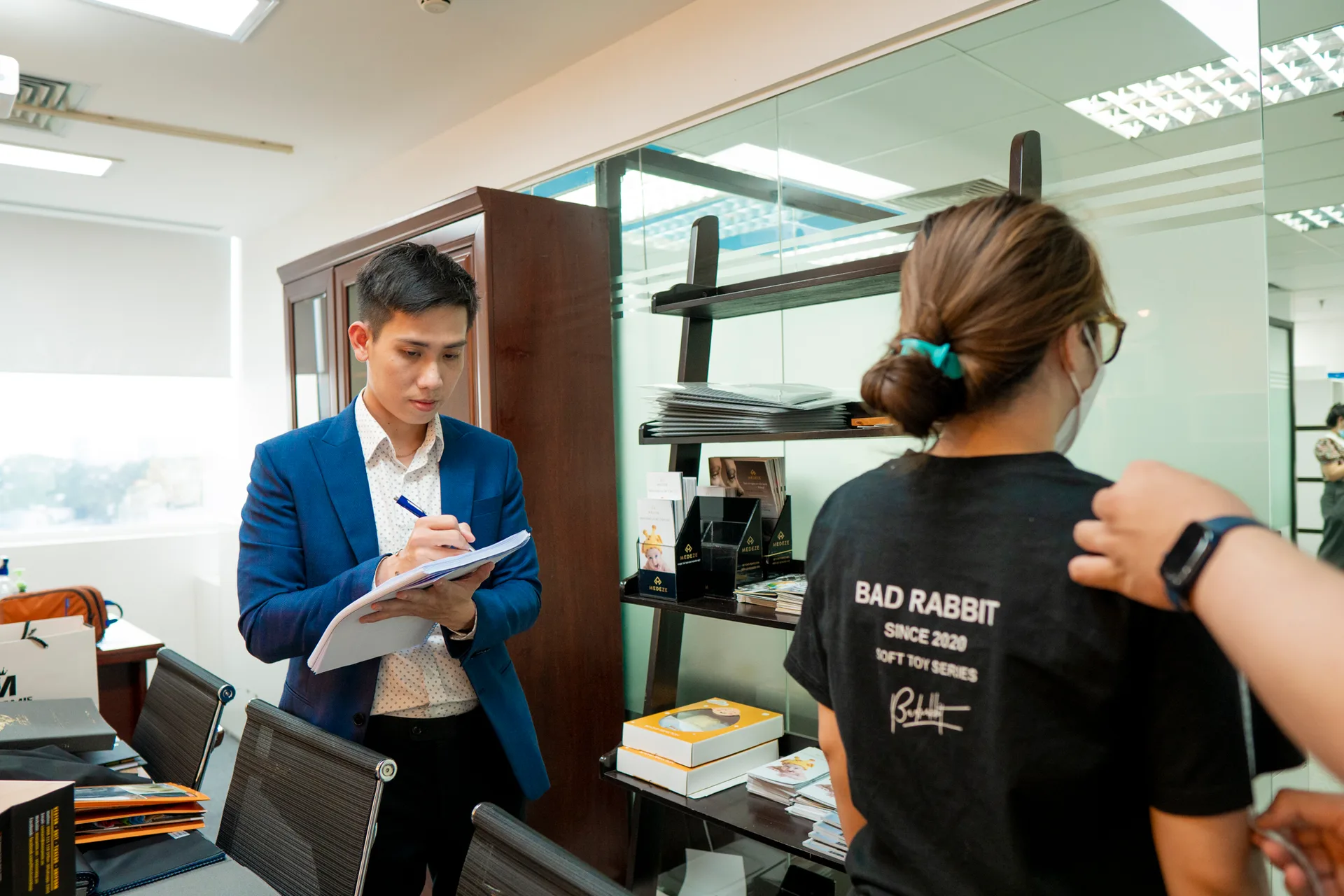 Nhân viên ghi phiếu số đo khi thợ may đo vai