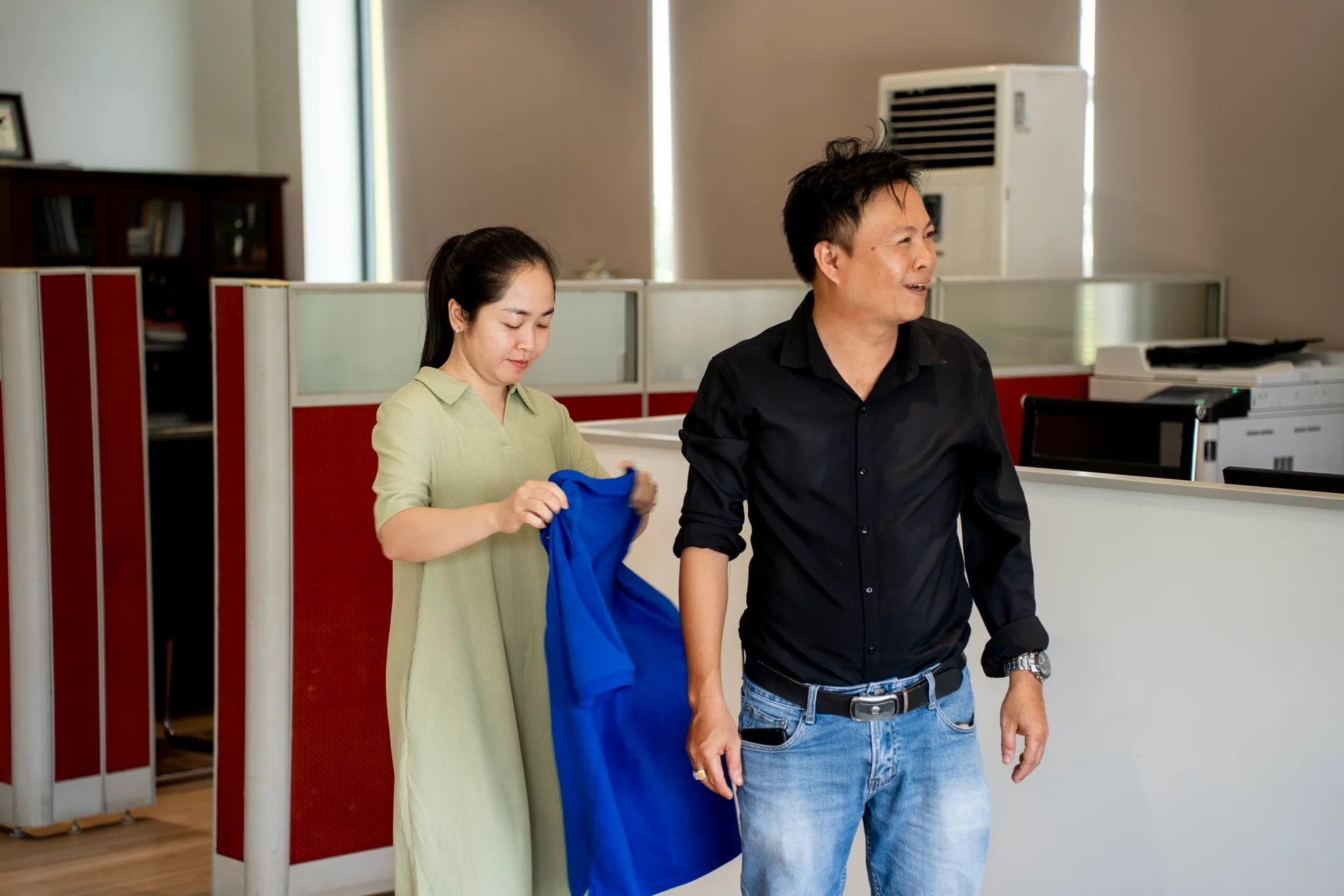 Nhân viên nữ xem áo polo xanh mẫu trước khi đo