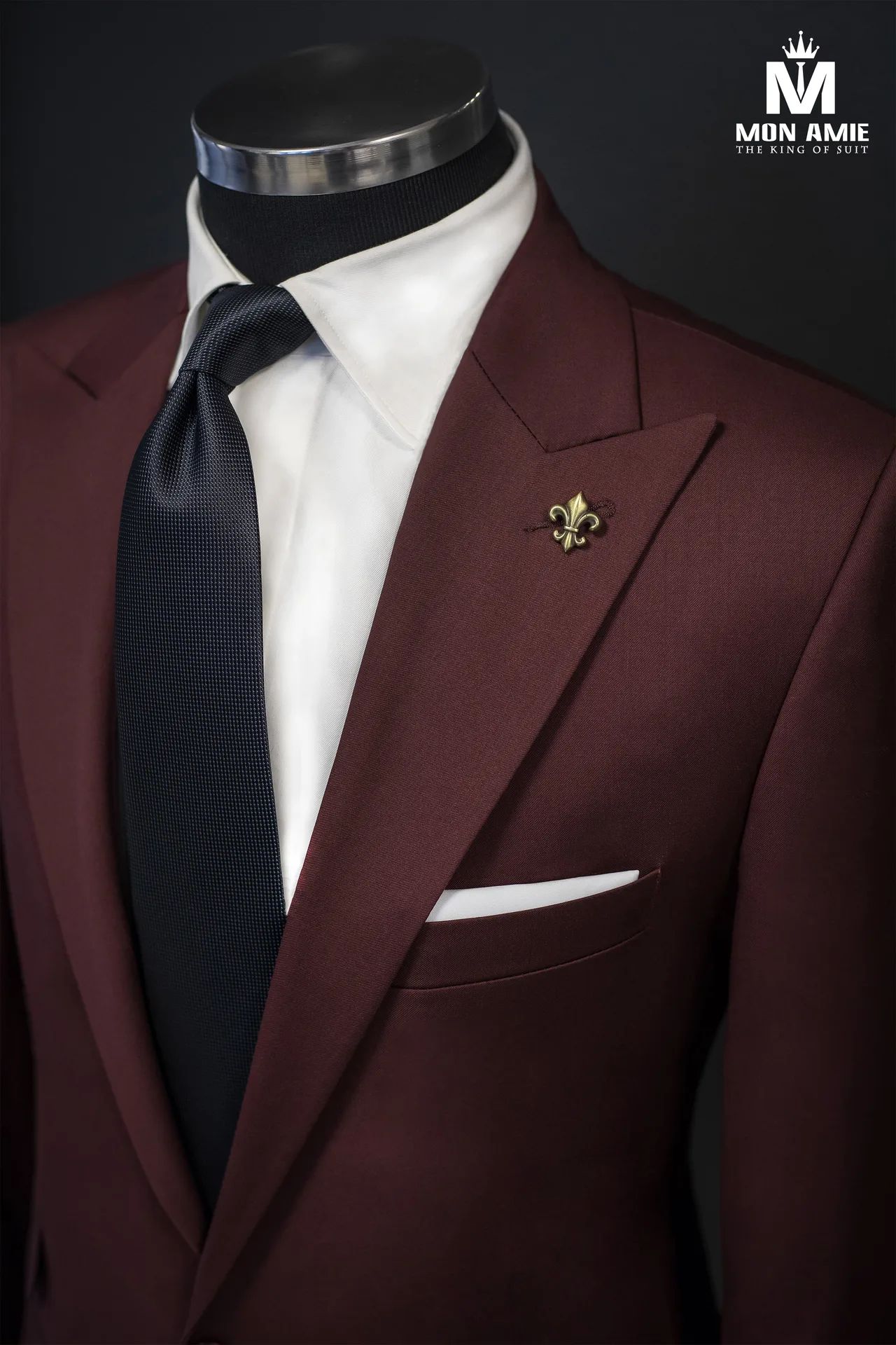 Cận cảnh ve áo suit đỏ đô, cà vạt navy và ghim cài hình hoa huệ